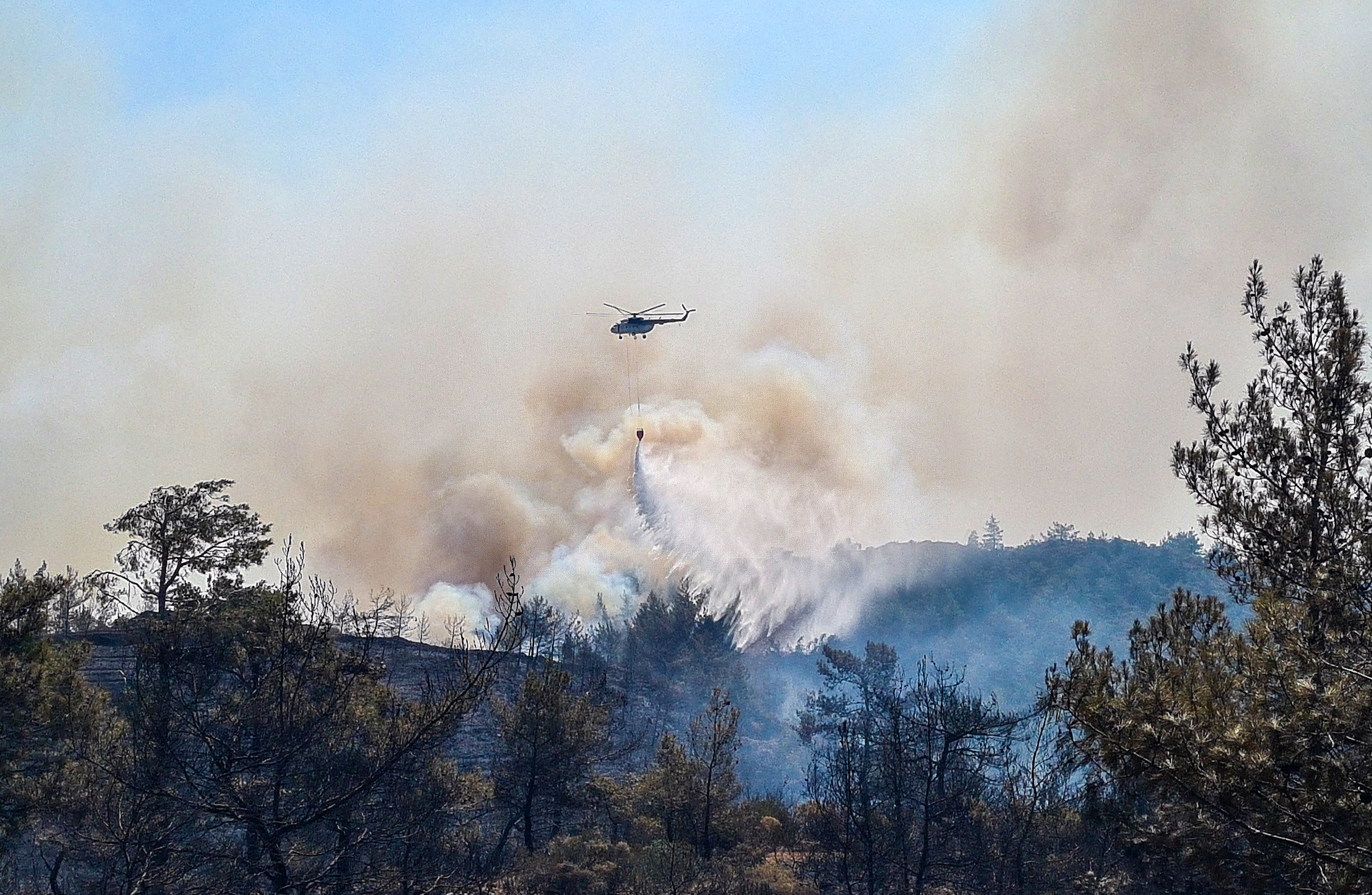 A firefighting helicopter drops water on a wildfire near Marmaris, a town in Mugla province, Turkey, June 22, 2022. REUTERS/Kenan Gurbuz