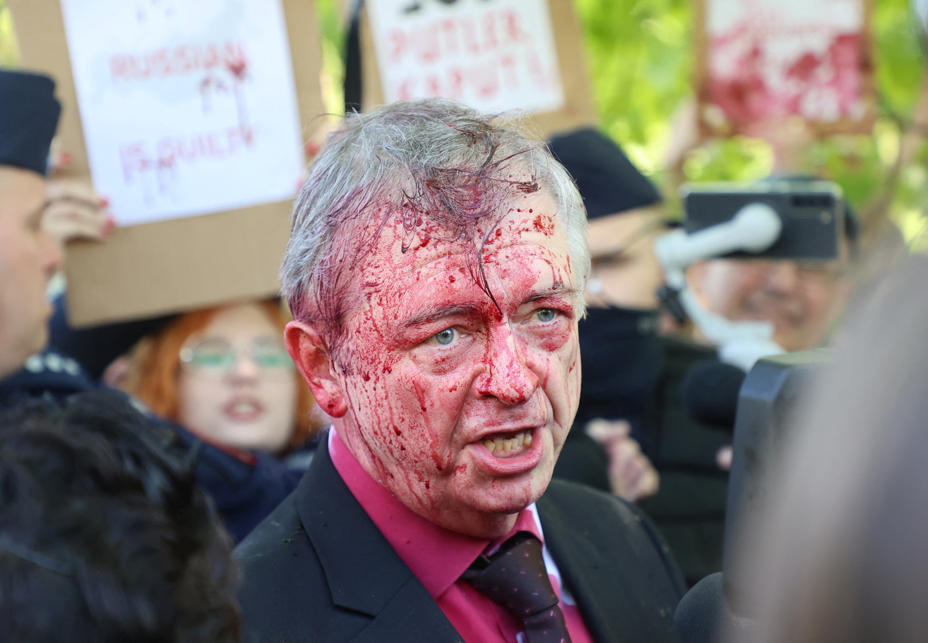 Russia's ambassador to Poland Sergey Andreev is covered in red substance thrown by protesters as he came to celebrate Victory day at the Soviet Military Cemetery in Warsaw