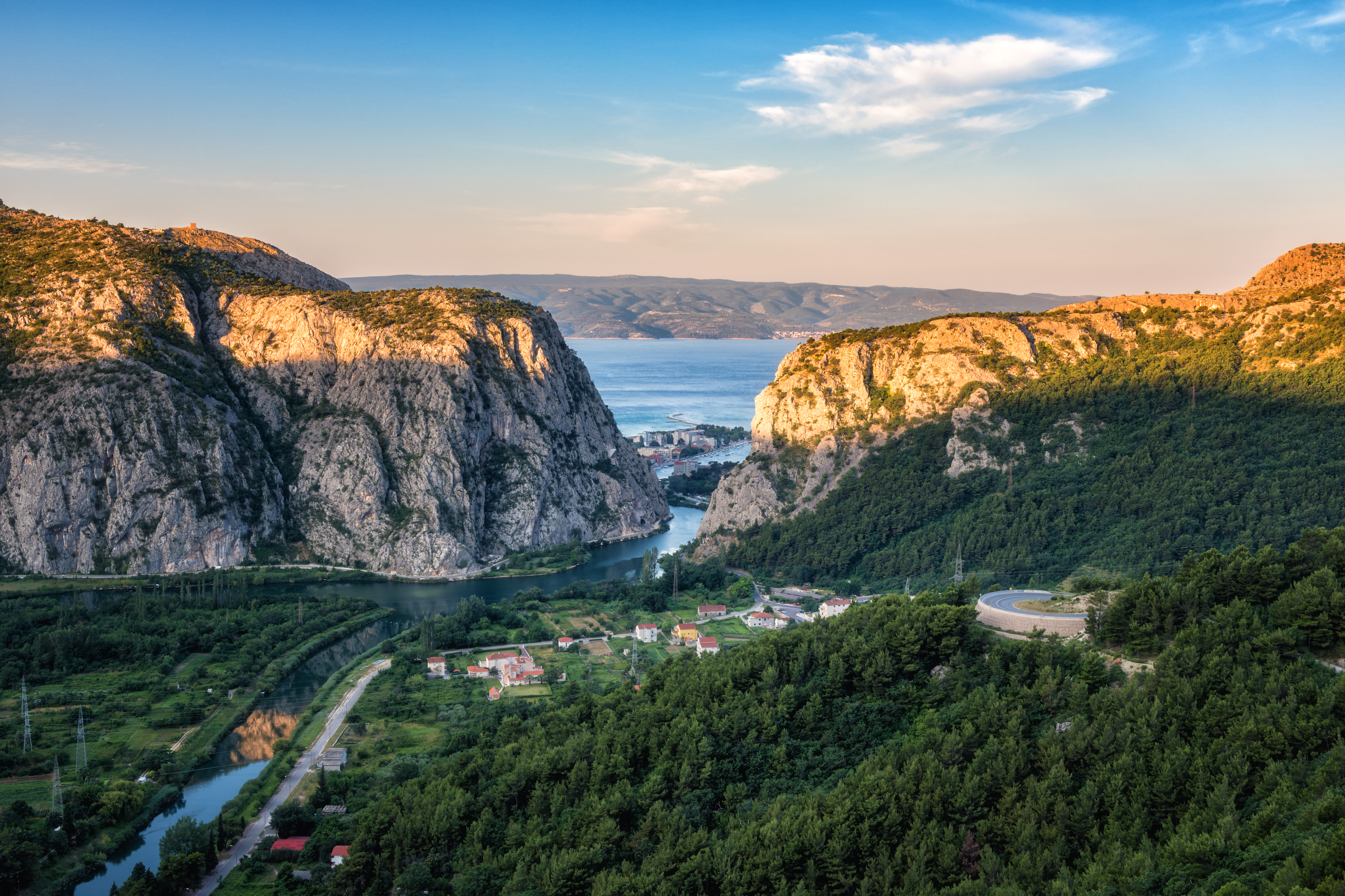Panoramski pogled na kanjon i ušće (ušće) reke Cetine, grad Omiš i ostrvo Brač ​​u Jadranskom moru kroz stenovite planine Dinare, Hrvatska