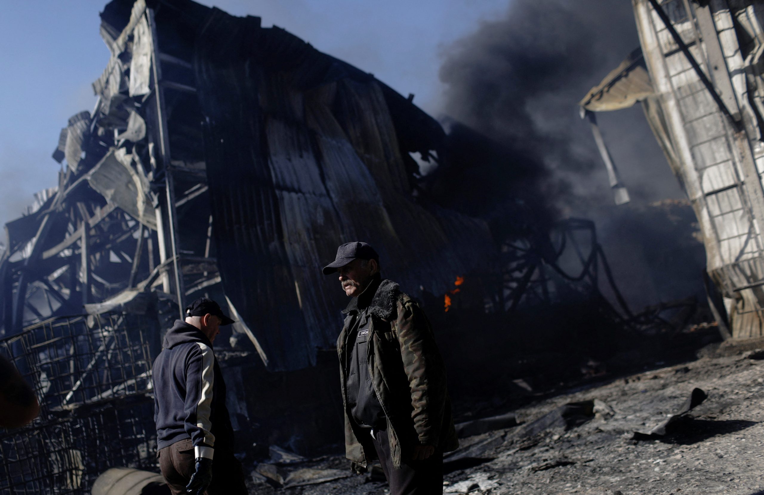 People walk at a damaged area inside a burning plant, following Russian shelling amid Russia's attack on Ukraine, in Kharkiv, Ukraine, April 30, 2022. REUTERS/Ricardo Moraes