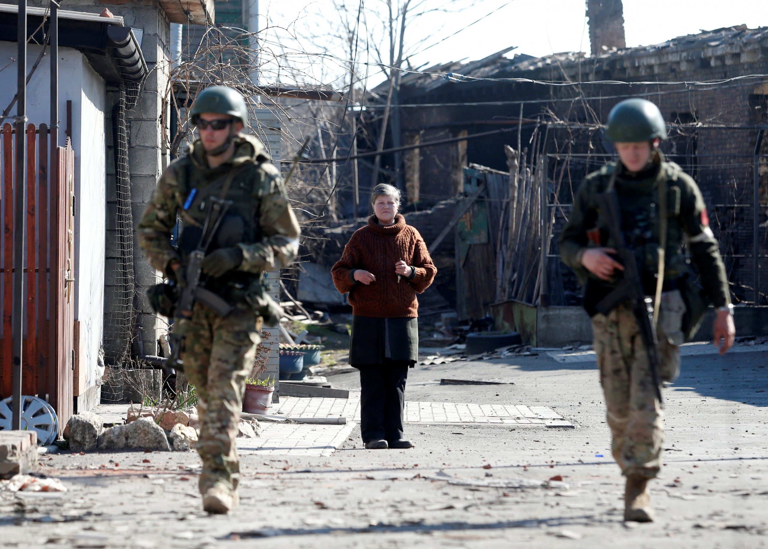 A local resident looks on as service members of pro-Russian troops inspect streets during Ukraine-Russia conflict in the southern port city of Mariupol, Ukraine April 7, 2022. REUTERS/Alexander Ermochenko