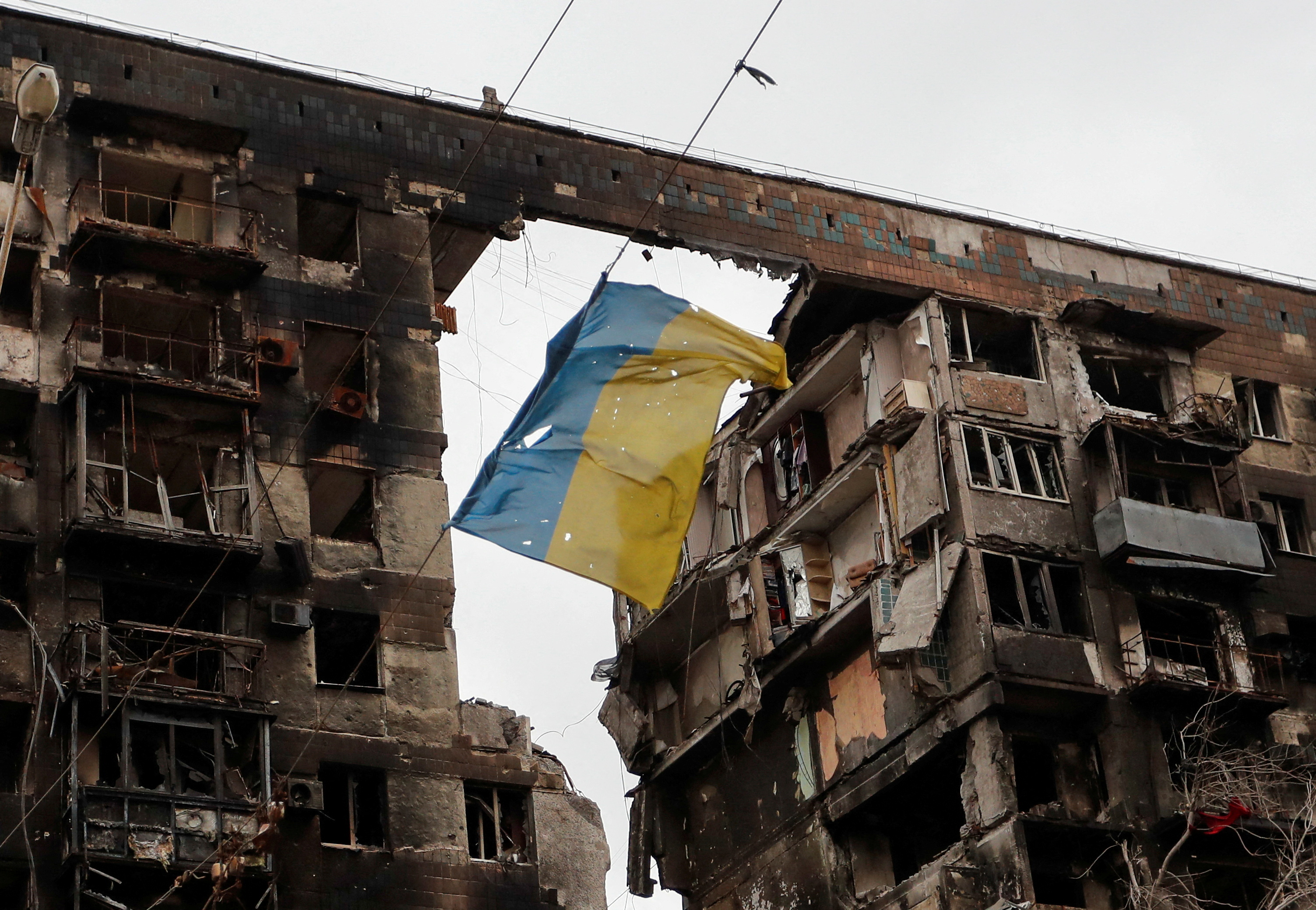 A view shows a torn flag of Ukraine hung on a wire in front an apartment building destroyed during Ukraine-Russia conflict in the southern port city of Mariupol, Ukraine April 14, 2022. REUTERS/Alexander Ermochenko     TPX IMAGES OF THE DAY