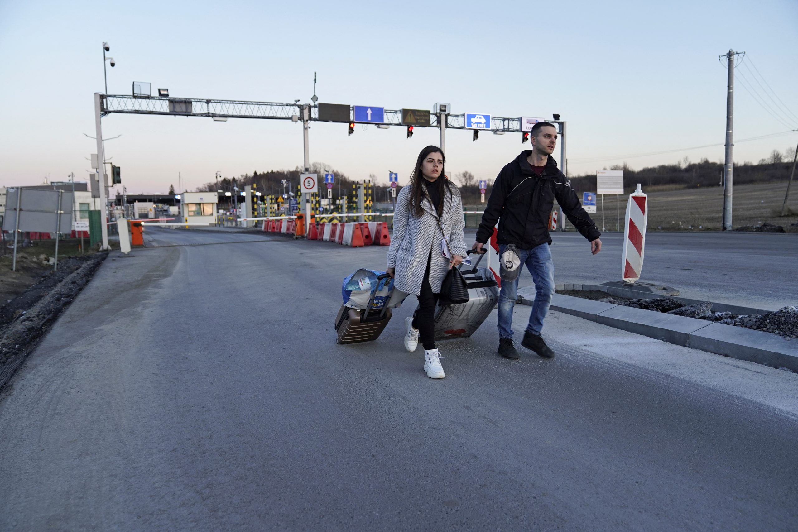 A couple, fleeing the violence in Ukraine, walk through the vehicle checkpoint lines at the border crossing, in Medyka, Poland, February 24, 2022. REUTERS/Bryan Woolston