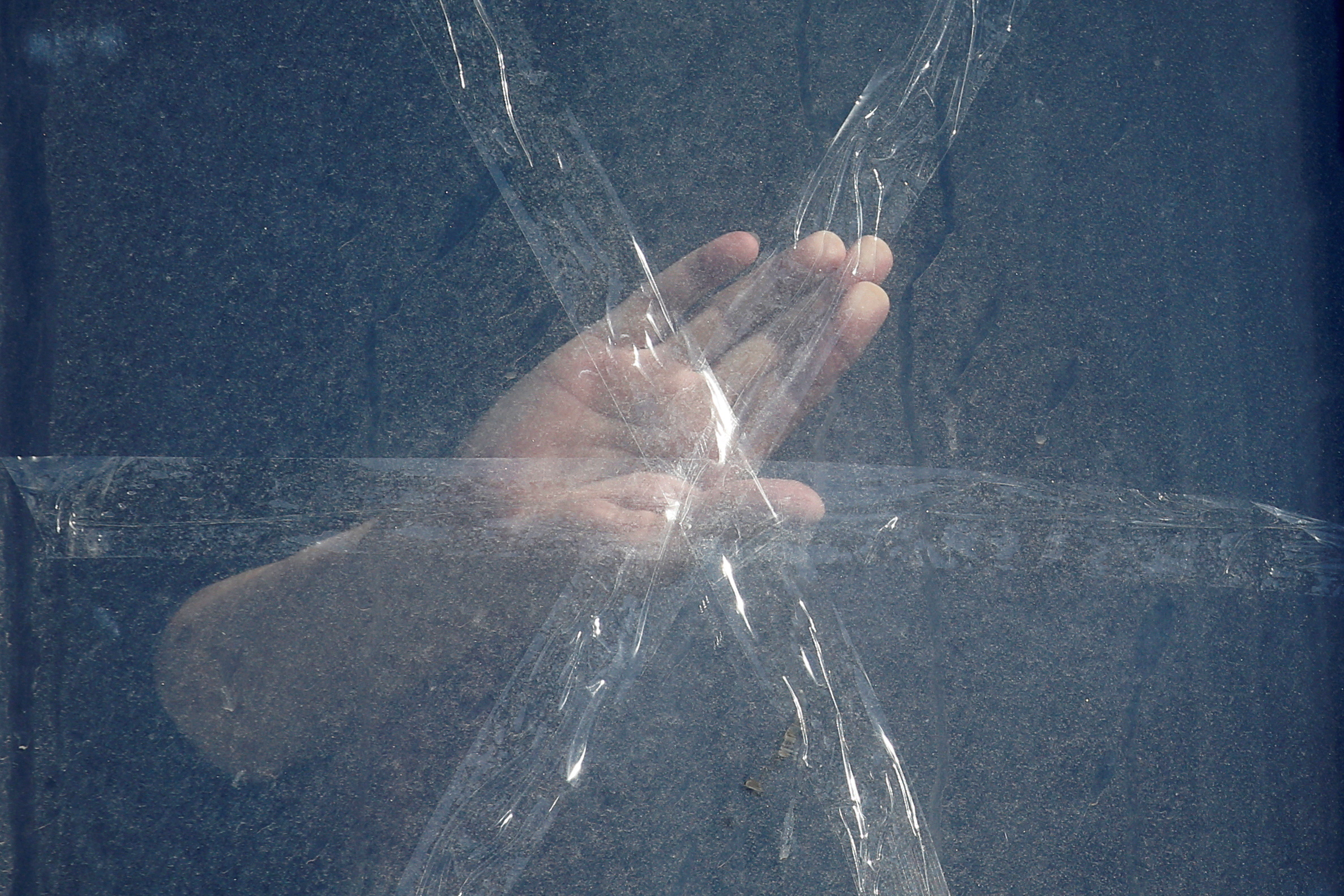 A local resident applies sticky tape to their window, near the site of night fighting with Russian troops, after Russia launched a massive military operation against Ukraine, in Kyiv, Ukraine February 26, 2022. REUTERS/Valentyn Ogirenko