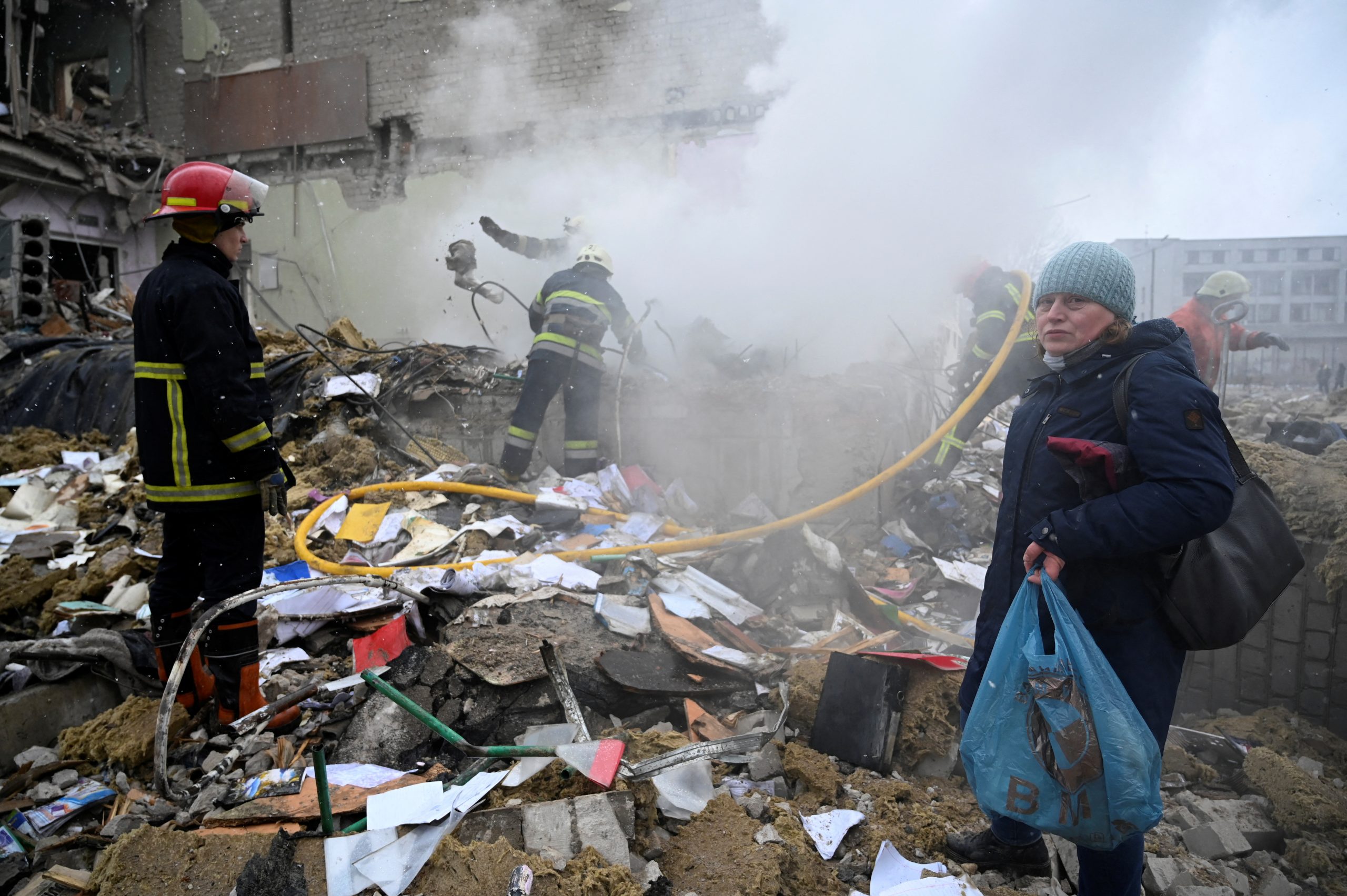 A woman stands next to rescuers amidst the debris of a school building destroyed by shelling, as Russia's invasion of Ukraine continues, in Zhytomyr, Ukraine March 4, 2022. REUTERS/Viacheslav Ratynskyi