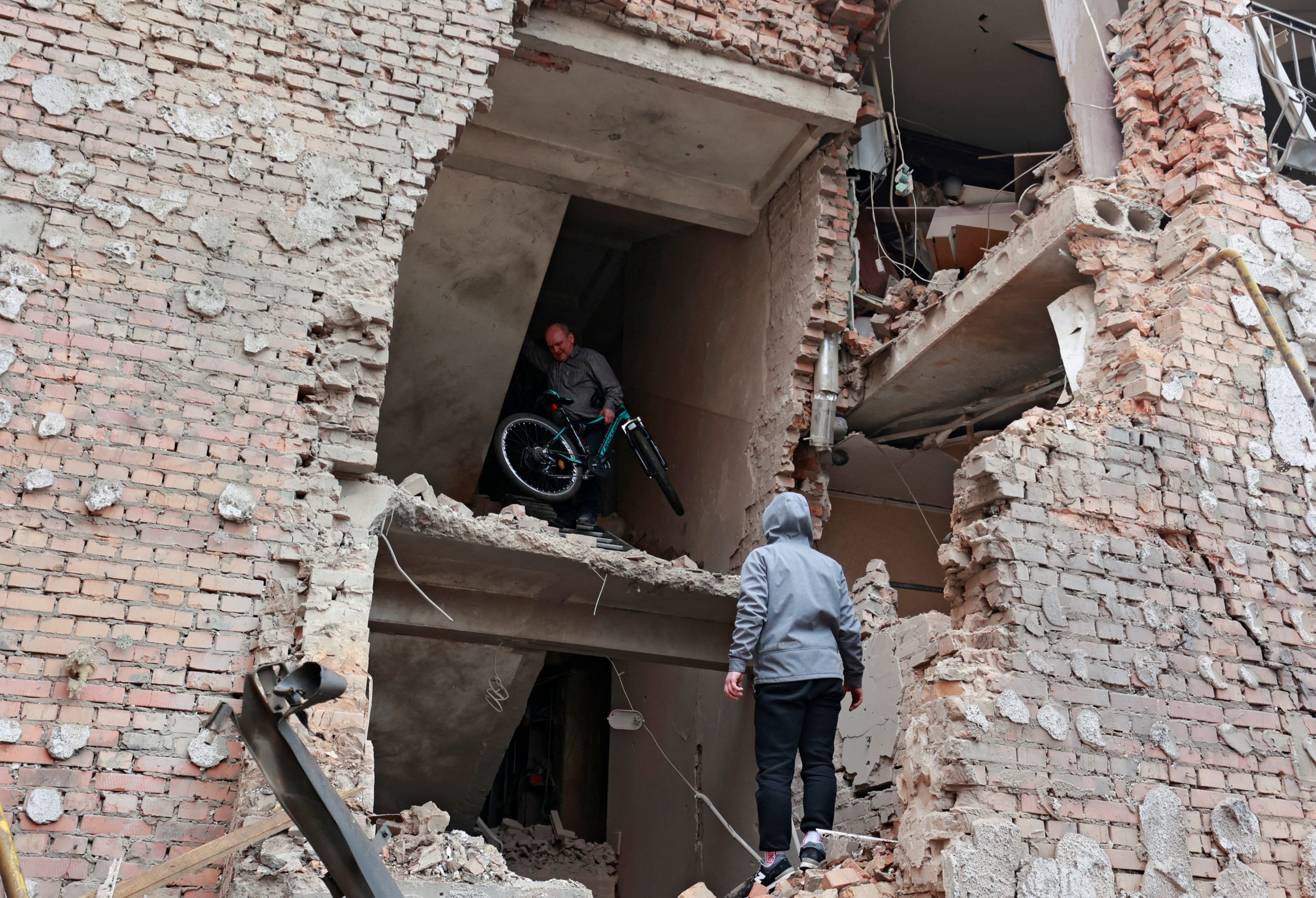 A man carries a bicycle out of a residential building destroyed by recent shelling, as Russia's invasion of Ukraine continues, in the city of Irpin in the Kyiv region, Ukraine March 2, 2022. REUTERS/Serhii Nuzhnenko