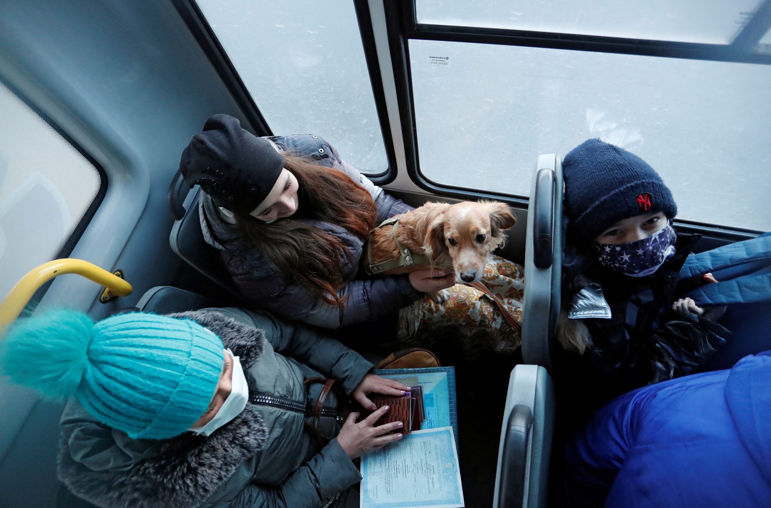 A woman holds her dog inside a bus during the evacuation of local residents to Russia, in the rebel-controlled city of Donetsk, Ukraine February 19, 2022. REUTERS/Alexander Ermochenko