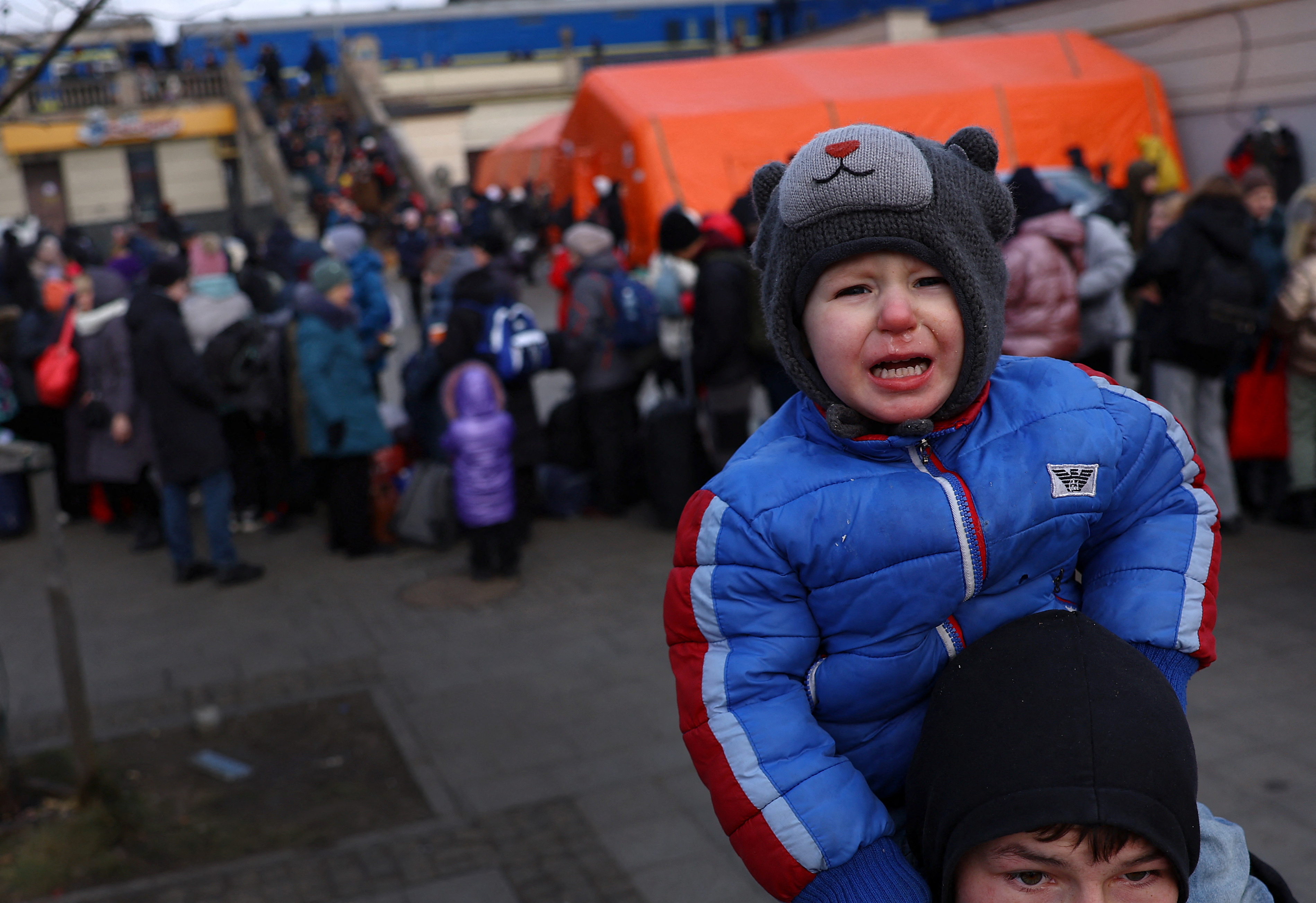A young boy cries sitting on the shoulders of his brother as they search for their mother after fleeing the ongoing Russian invasion of Ukraine, outside the train station in Lviv, Ukraine, March 8, 2022. REUTERS/Kai Pfaffenbach