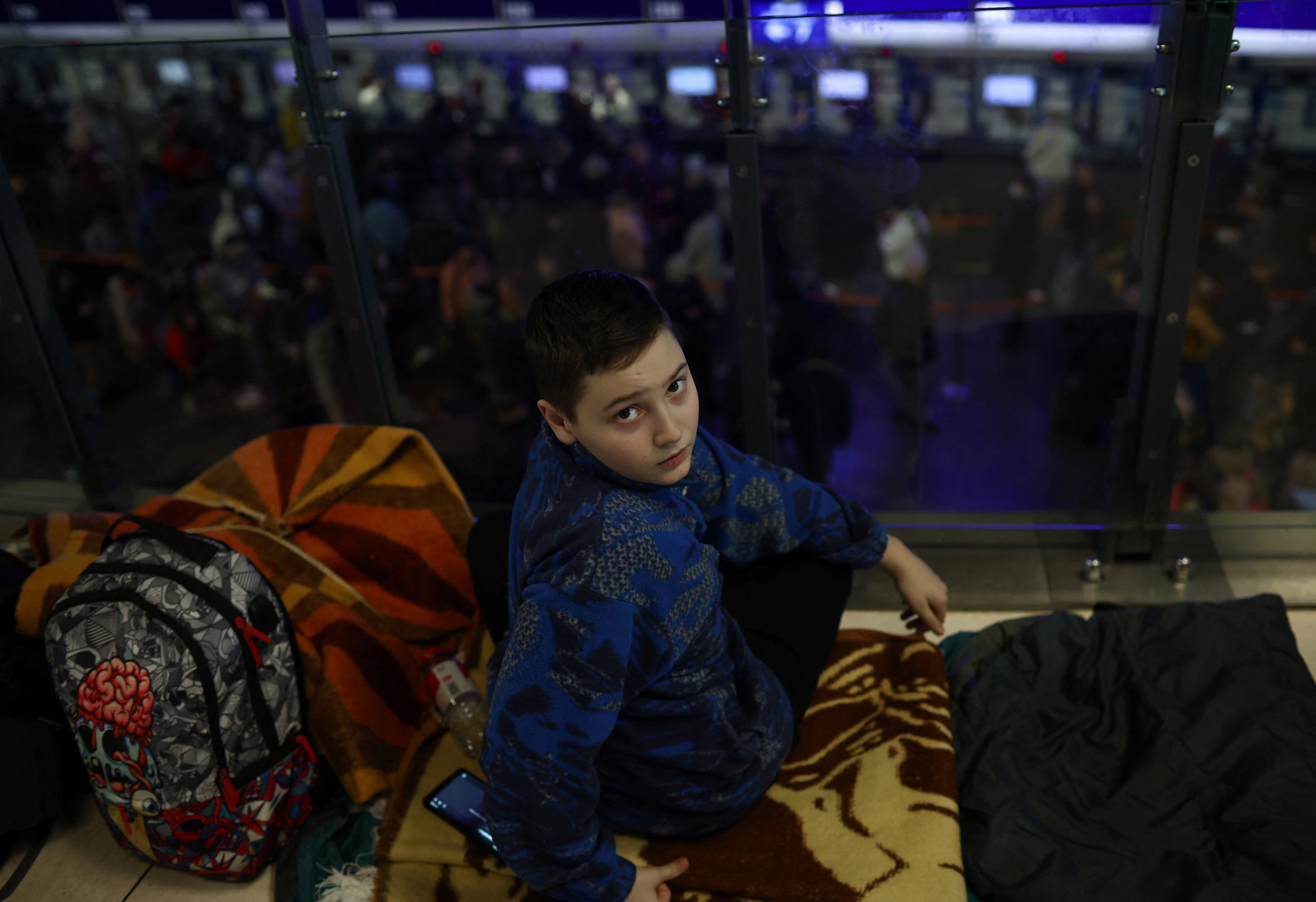 A boy looks on as he sits on a floor at the main hall of the Central train station, following the Russian invasion of Ukraine, in Warsaw, Poland March 9, 2022. REUTERS/Kacper Pempel