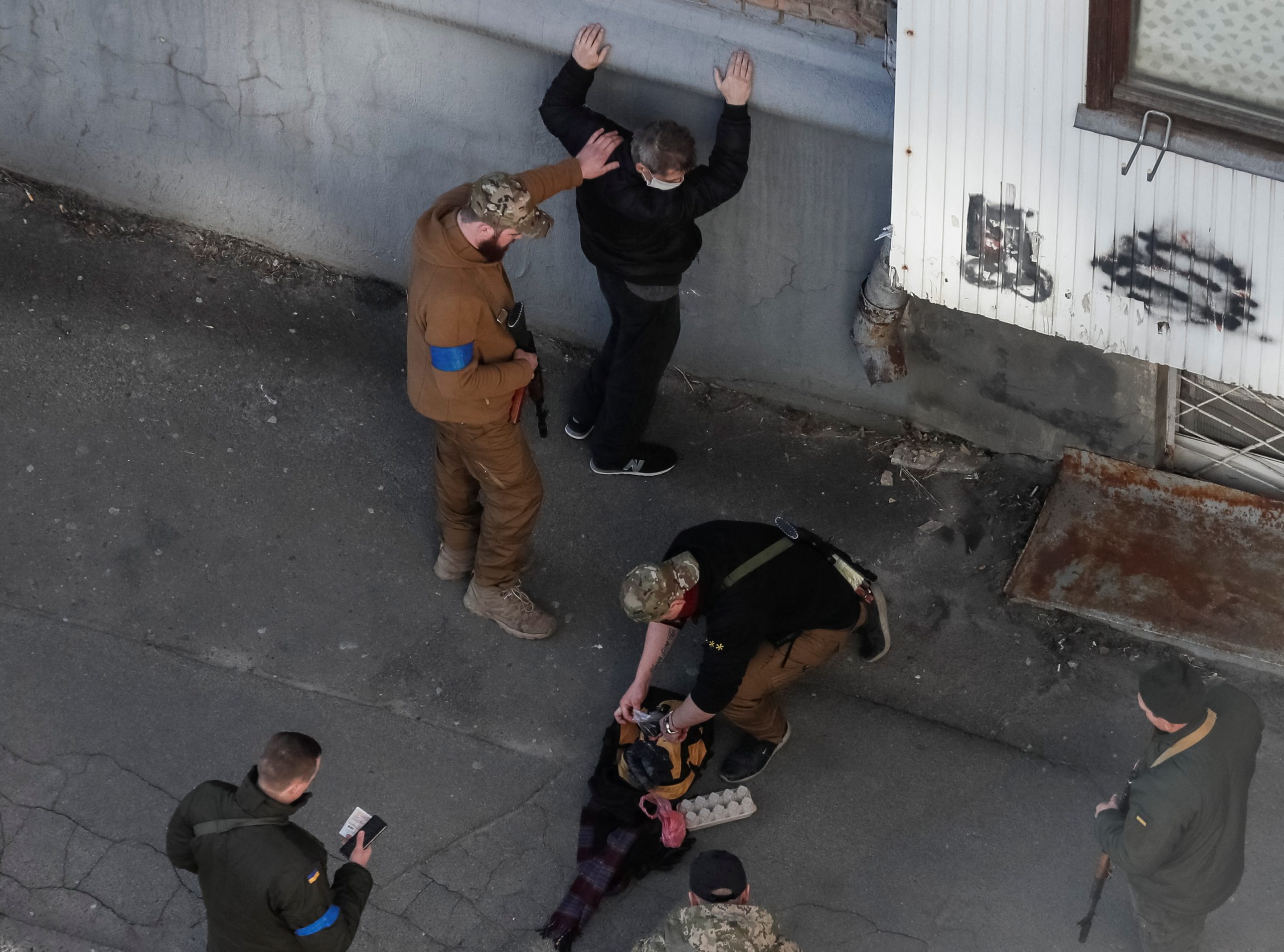Members of the Ukrainian Territorial Defense Forces check a man as they patrol during a long curfew in Kyiv, Ukraine March 22, 2022. REUTERS/Gleb Garanich
