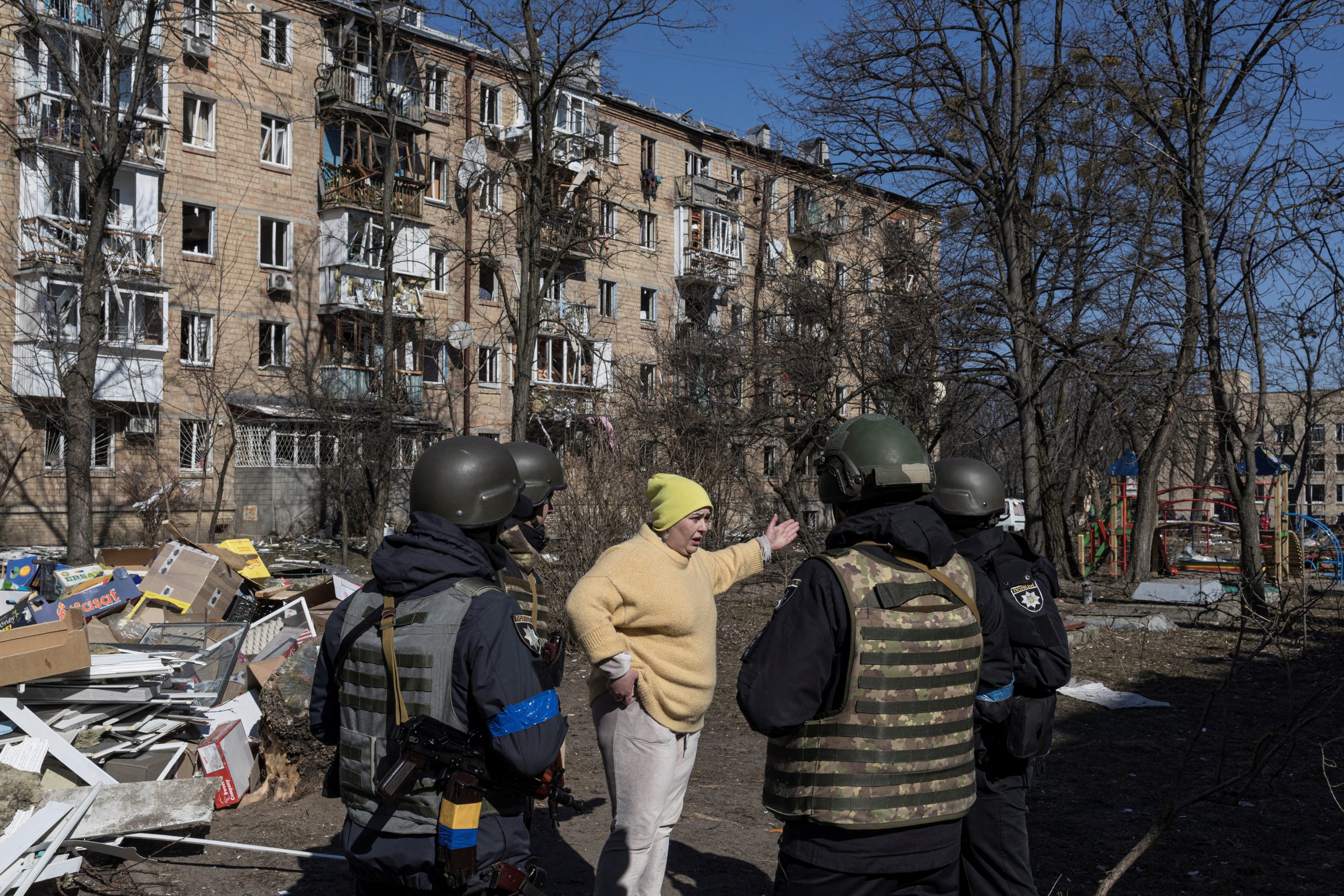A woman talks to Ukrainian servicemen at a residential district that was damaged by shelling, as Russia's invasion of Ukraine continues, in Kyiv, Ukraine, March 18, 2022. REUTERS/Marko Djurica