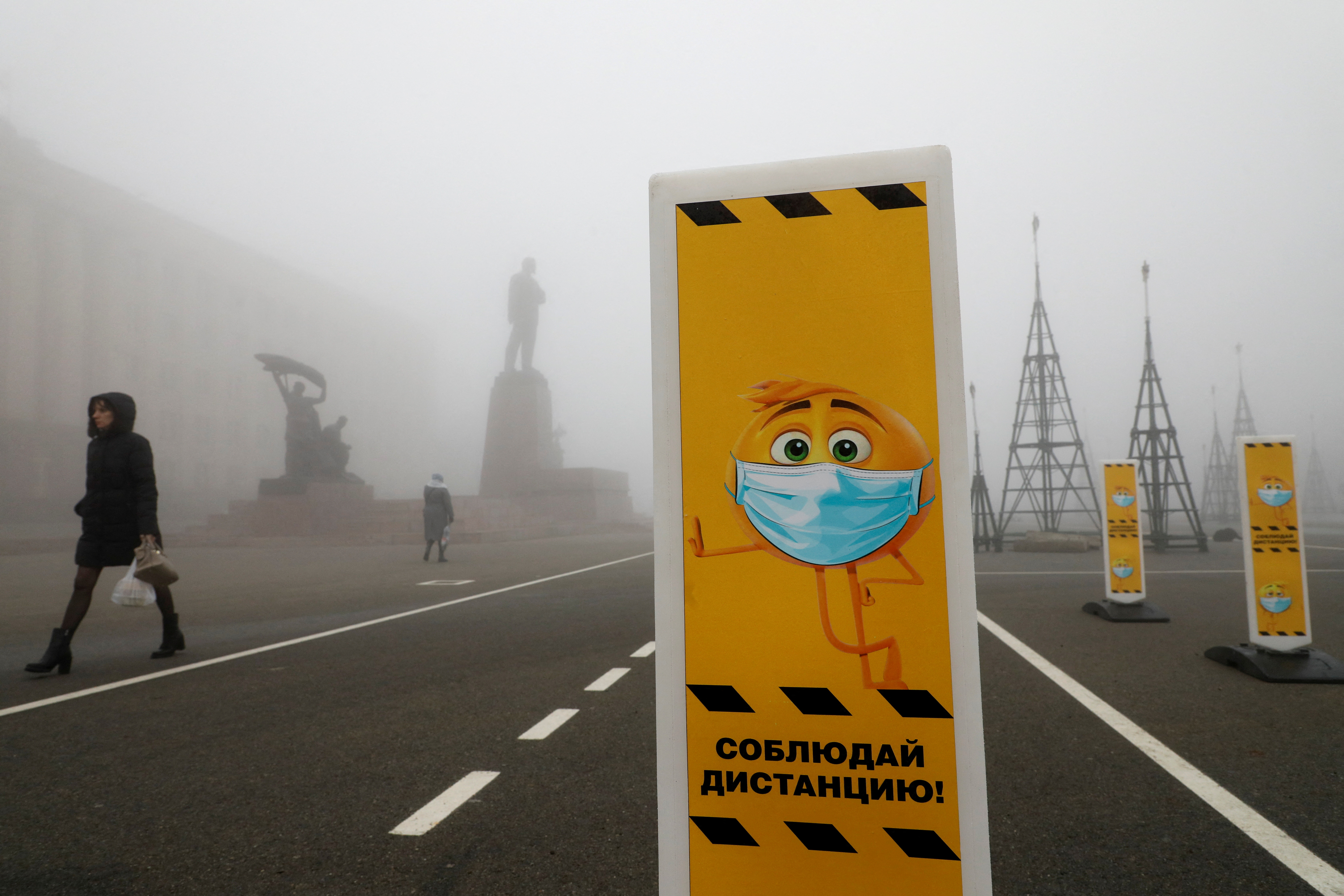 FILE PHOTO: Pedestrians walk past social distancing signs placed near a skating rink amid the coronavirus disease outbreak in Stavropol