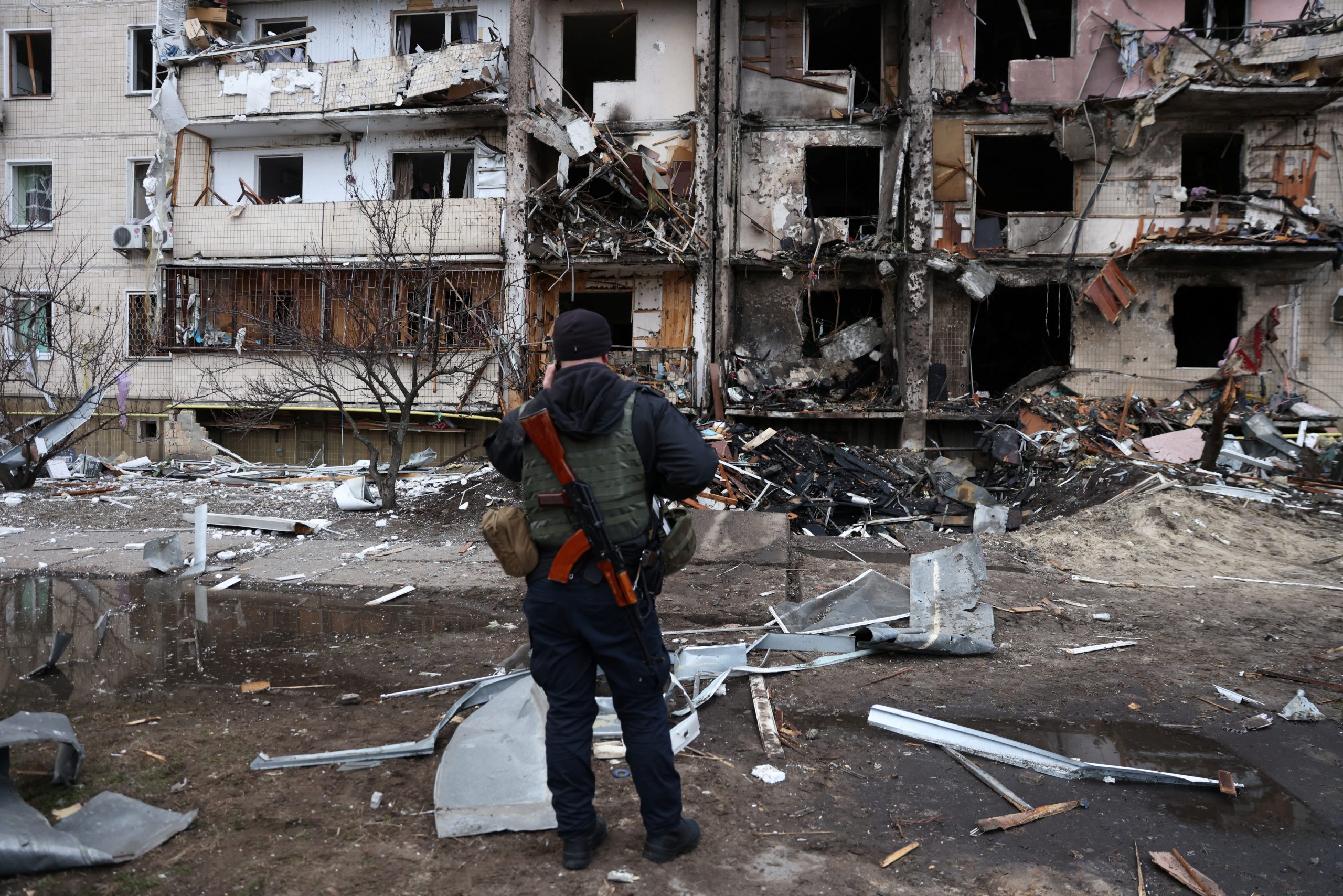 A person stands in front of a damaged residential building, after Russia launched a massive military operation against Ukraine, in Kyiv, Ukraine February 25, 2022. REUTERS/Umit Bektas