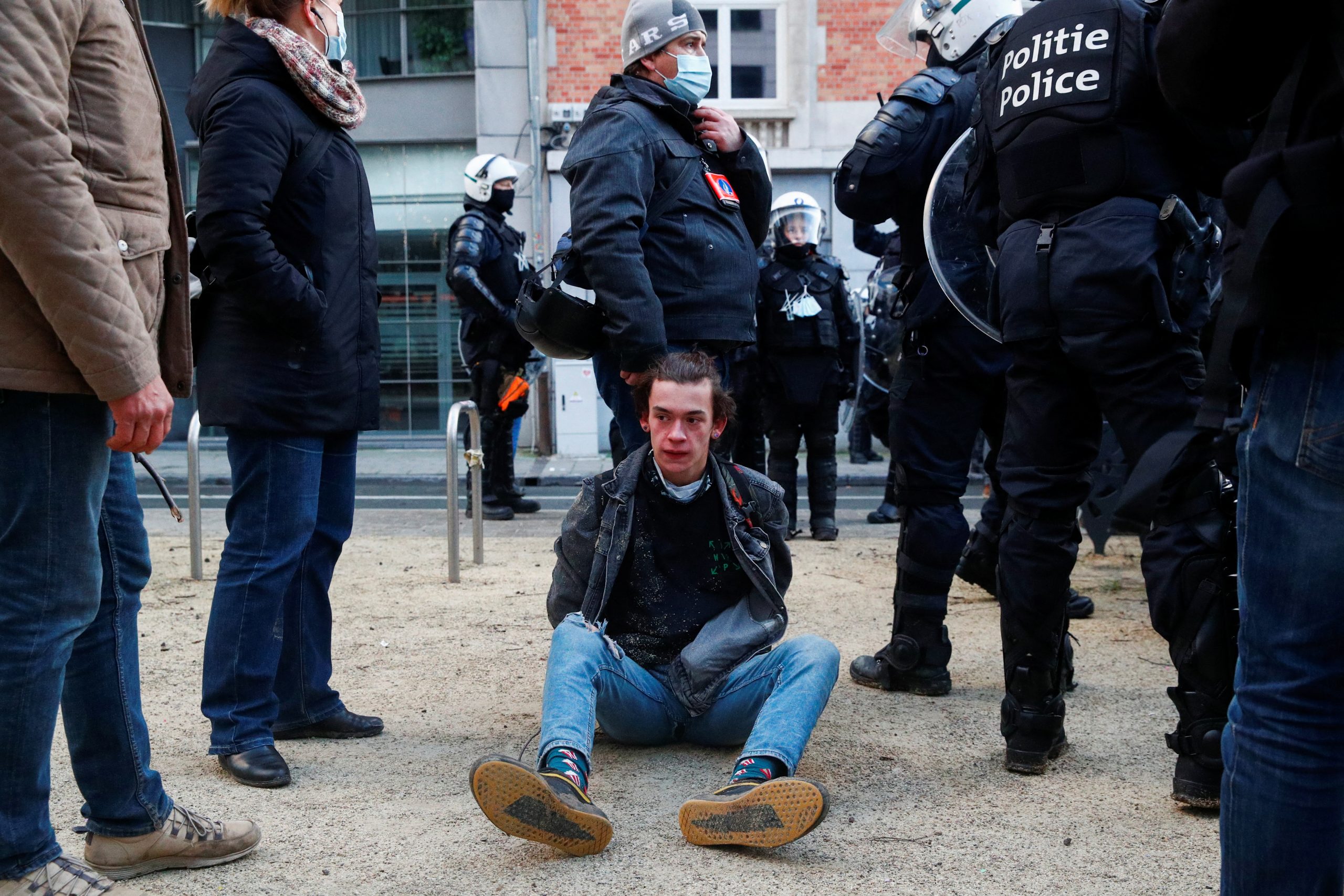 A person sits on the ground during a demonstration against the Belgian government's restrictions imposed to contain the spread of the coronavirus disease (COVID-19) in Brussels, Belgium January 9, 2022. REUTERS/Johanna Geron
