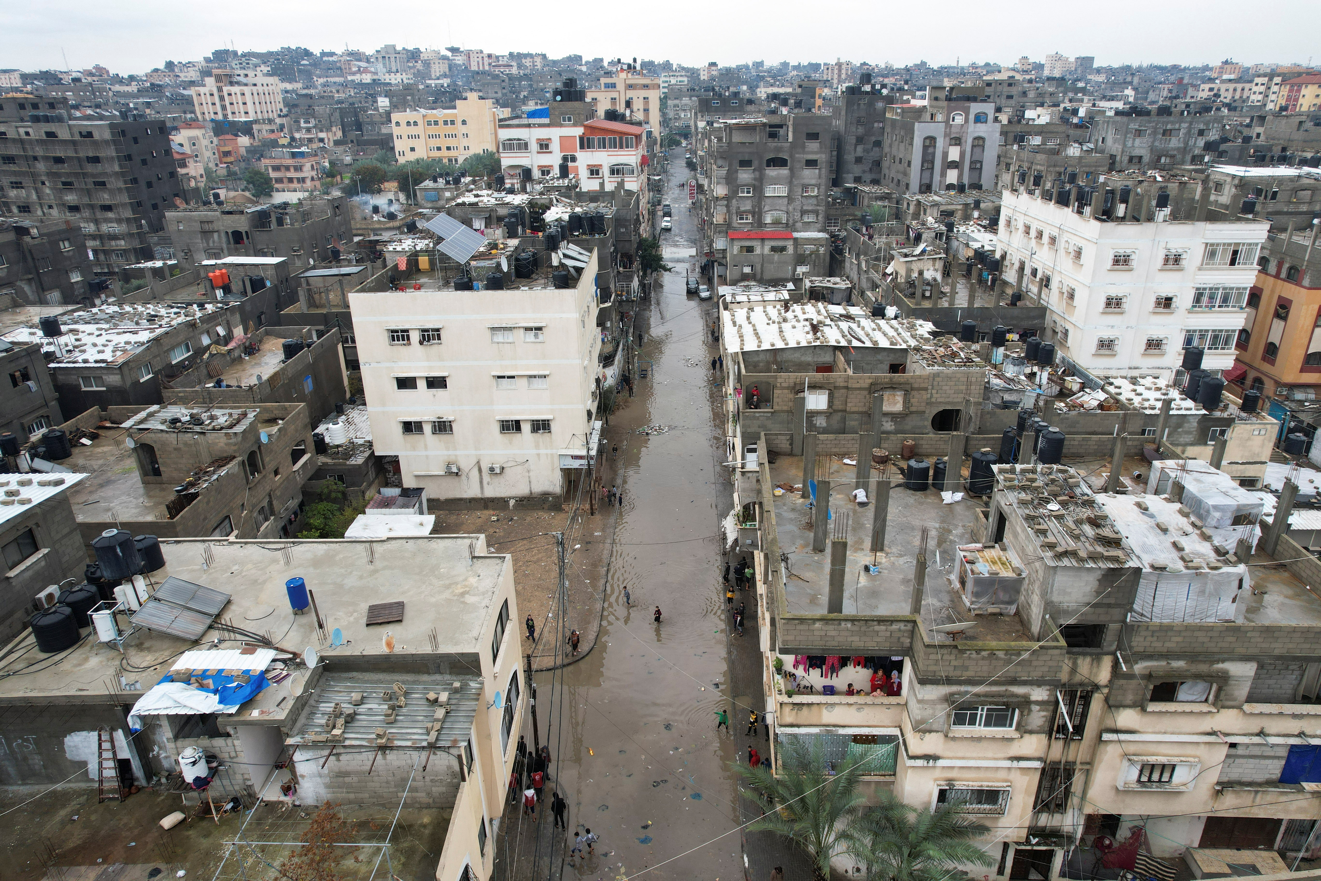 Palestinian children wade through a flooded road following heavy rains in the northern Gaza Strip, January 16, 2022. Picture taken with a drone. REUTERS/Mohammed Salem