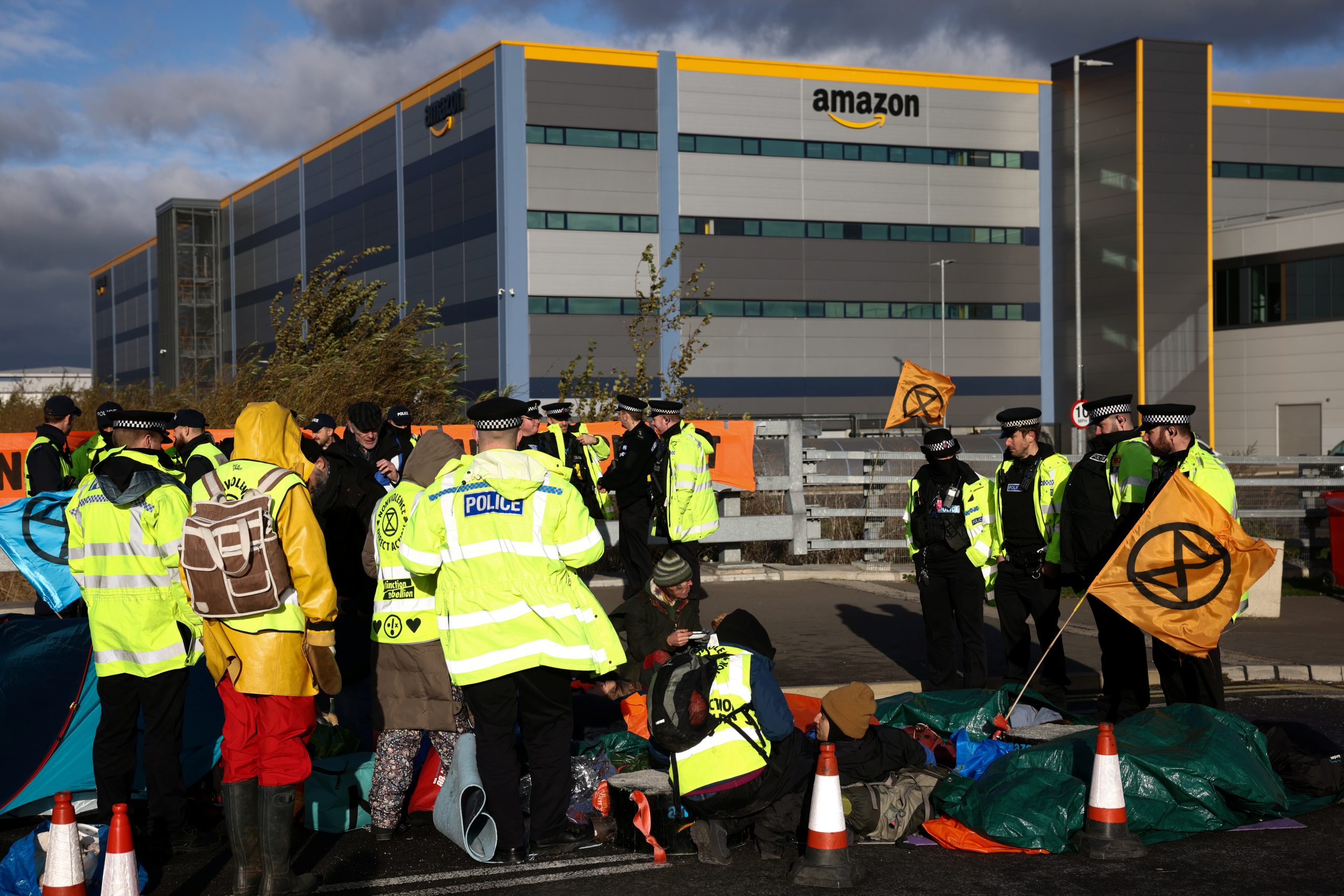Police officers speak with protesters, as Extinction Rebellion activists block a street outside an Amazon fulfilment centre in Tilbury, Essex, Britain, November 26, 2021. REUTERS/Henry Nicholls