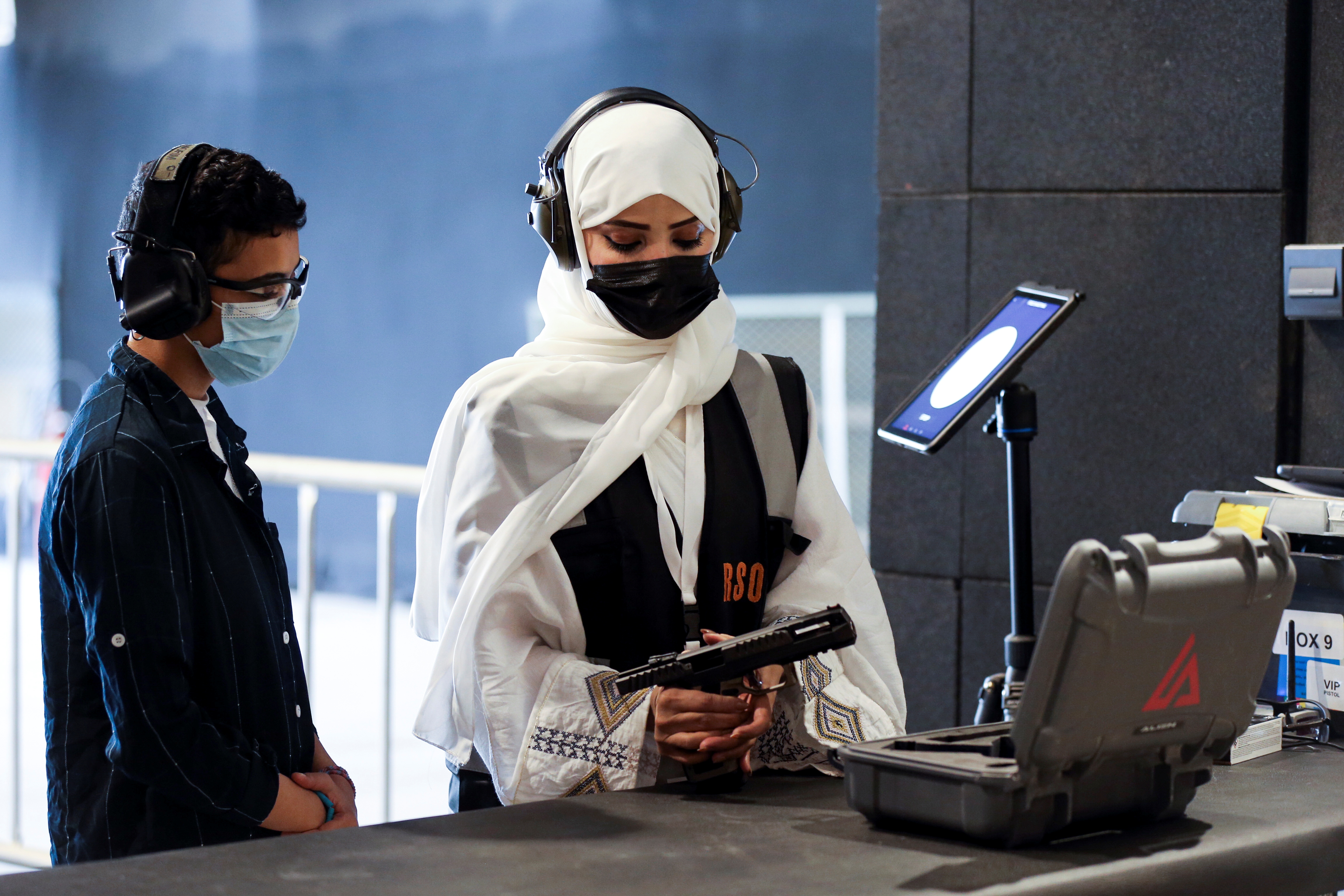 Saudi female firearm trainer teaches a Saudi woman on safe usage of weapons at the Top-Gun shooting range