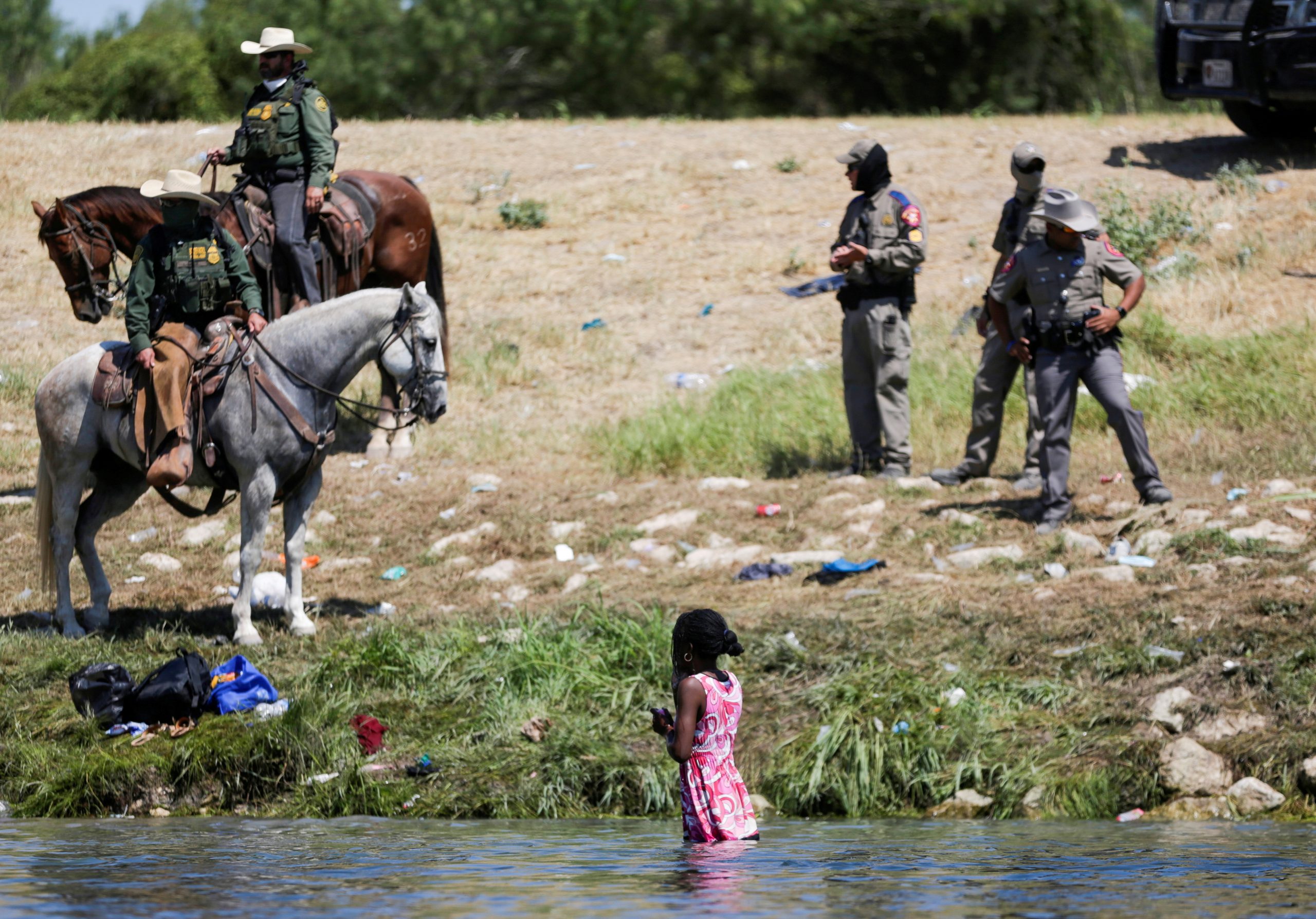 U.S. law enforcement officers on horseback stand near a young woman bathing in the Rio Grande, as seen from Ciudad Acuna, Mexico September 19, 2021. Picture taken September 19, 2021. REUTERS/Daniel Becerril     TPX IMAGES OF THE DAY