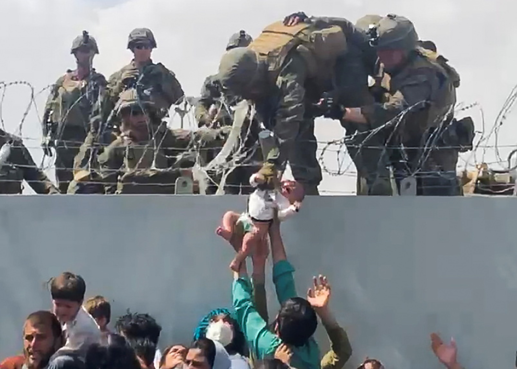 FILE PHOTO: A baby is handed over to the American army over the perimeter wall of the airport for it to be evacuated, in Kabul, Afghanistan, August 19, 2021. OMAR HAIDARI/via REUTERS/File Photo