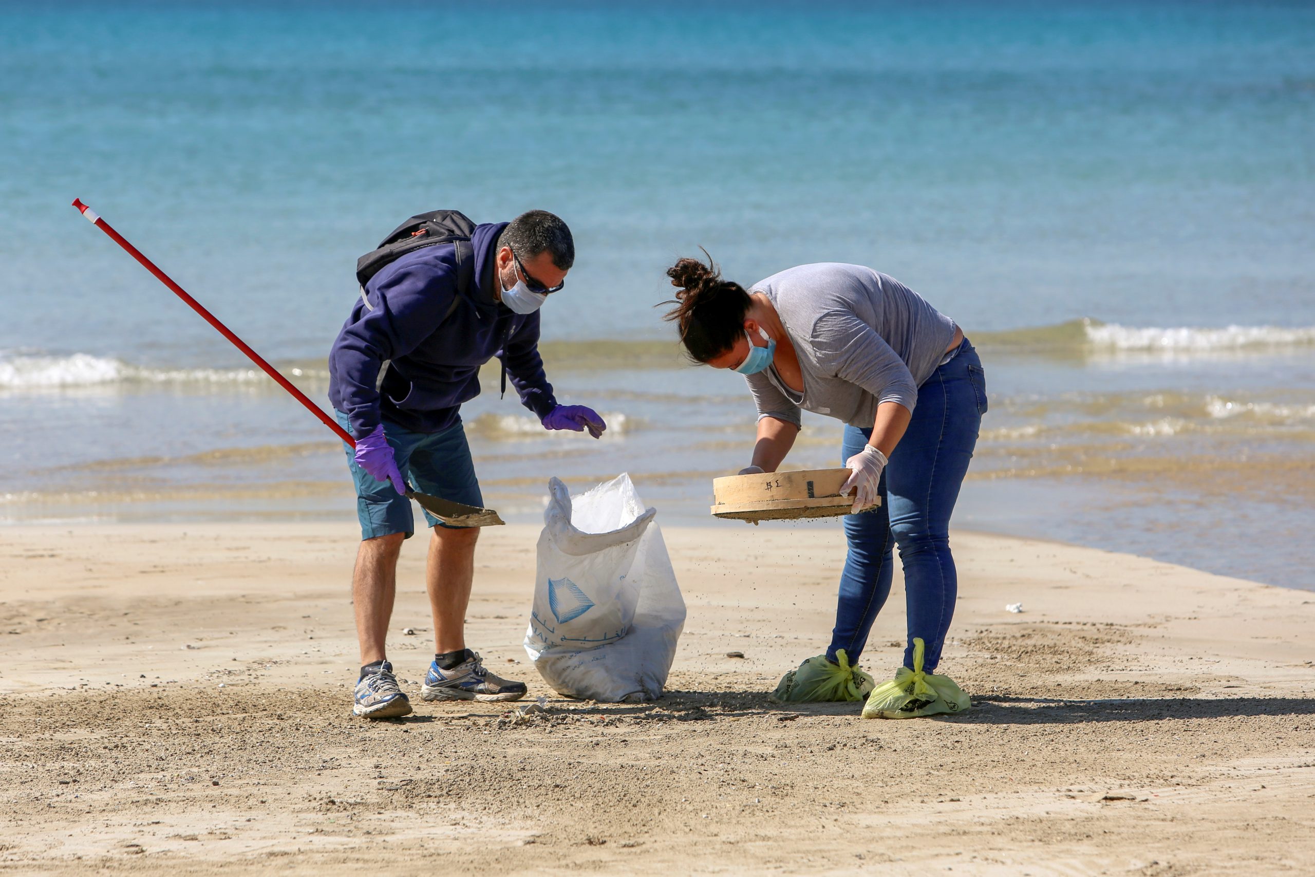 People clean a beach in the aftermath of an oil spill that drenched much of the Mediterranean shoreline in Tyre nature reserve, Lebanon February 27, 2021. REUTERS/Aziz Taher