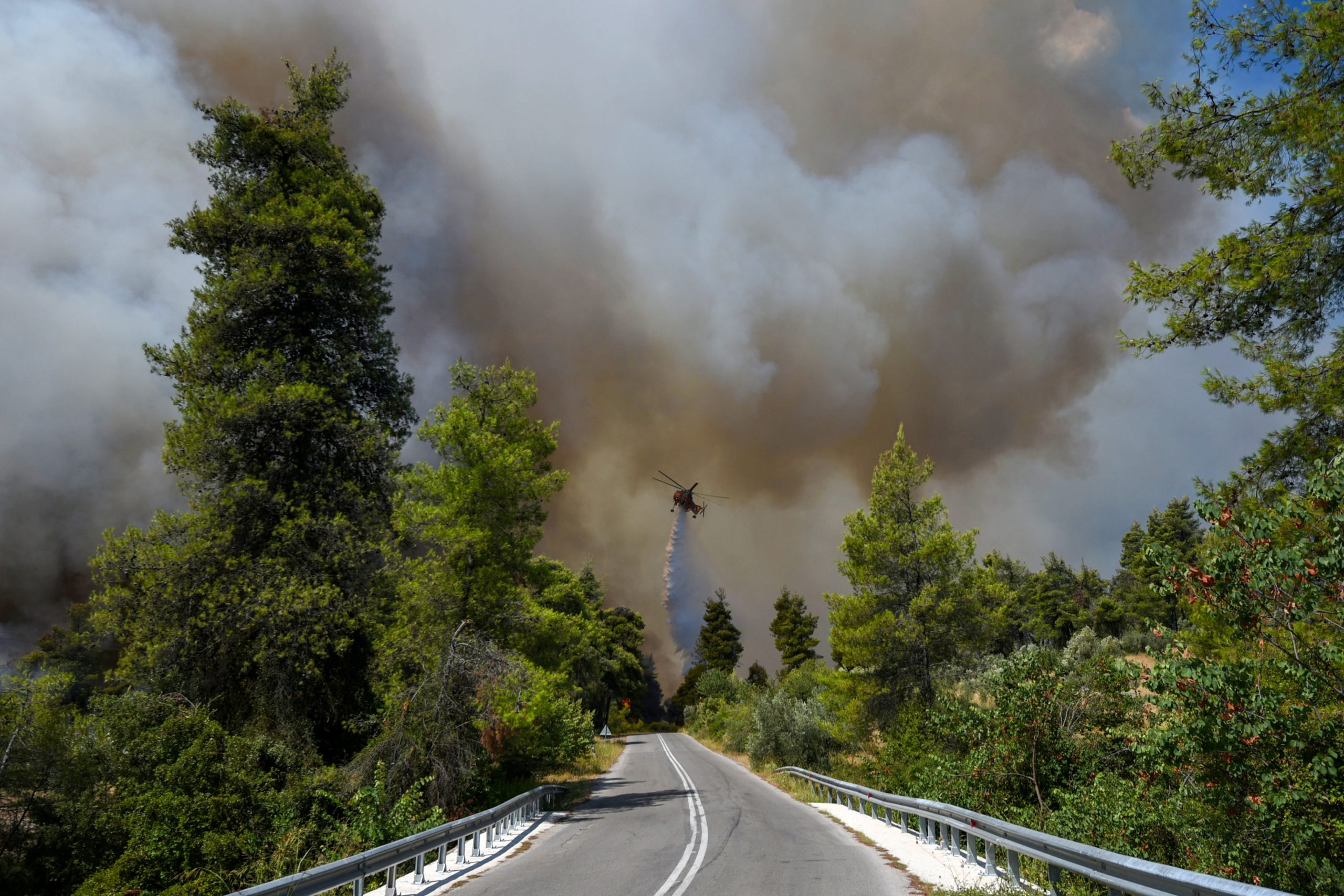 A firefighting helicopter makes a water drop as a wildfire burns near the village of Ellinika, on the island of Evia, Greece, August 8, 2021. REUTERS/Alexandros Avramidis