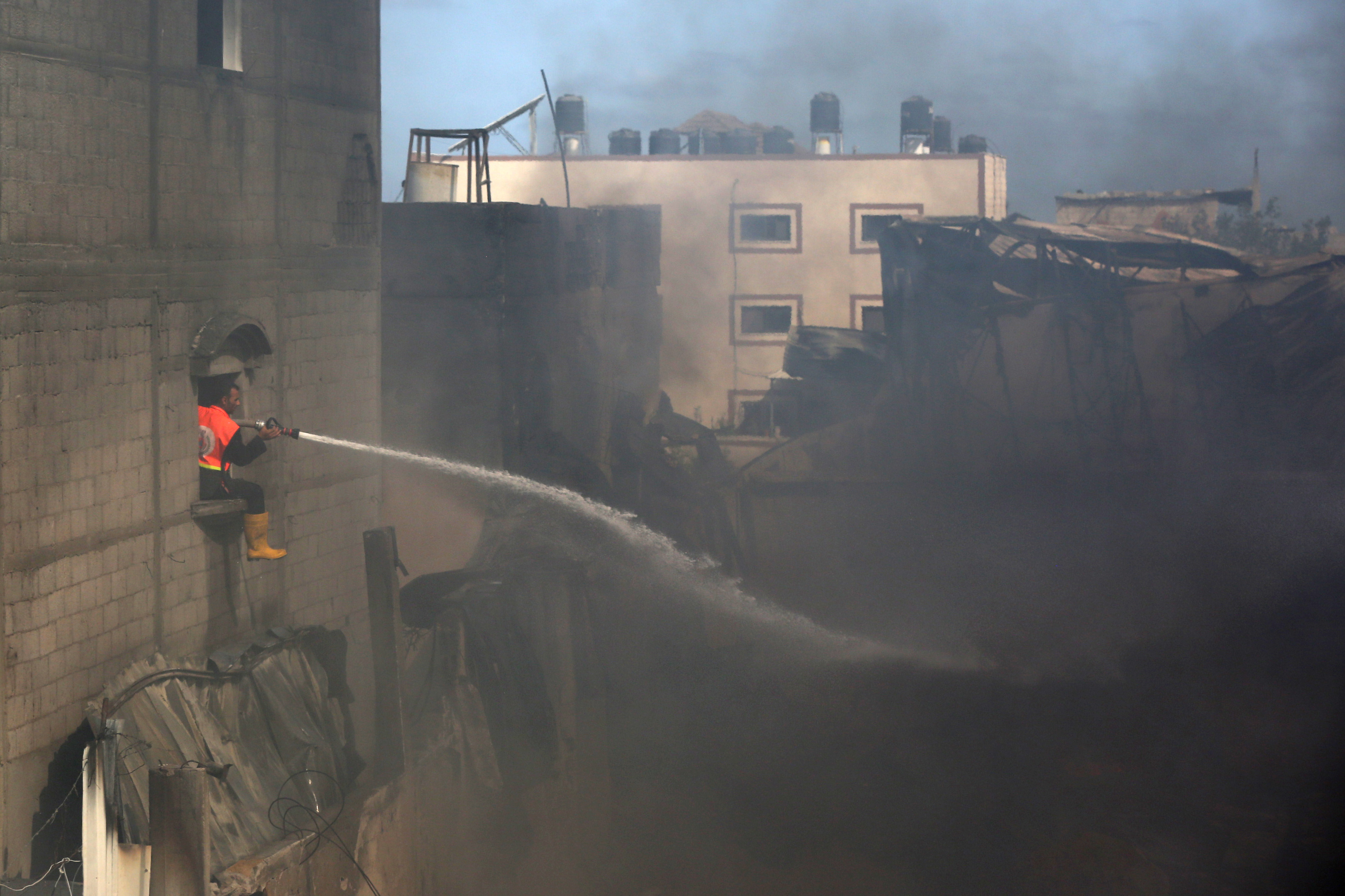 A Palestinian firefighter puts out a fire at a sponge factory after it was hit by Israeli artillery shells, according to witnesses, in the northern Gaza Strip May 17, 2021. REUTERS/Ashraf Abu Amrah NO RESALES. NO ARCHIVES.