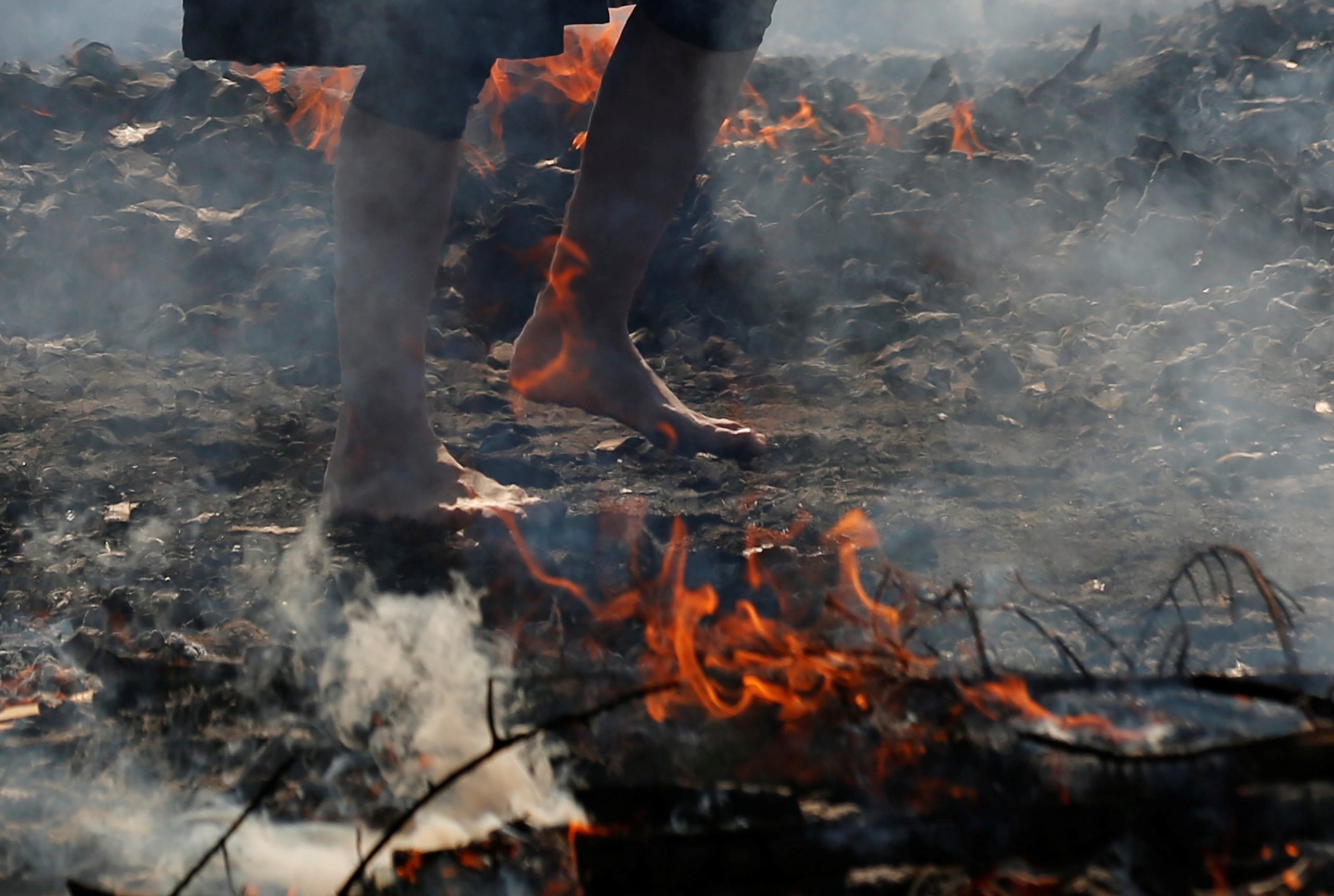 A womaN walks across smoldering hot ground at the fire-walking festival, called hiwatari matsuri in Japanese, at Mt.Takao in Tokyo, Japan, March 14, 2021. REUTERS/Kim Kyung-Hoon