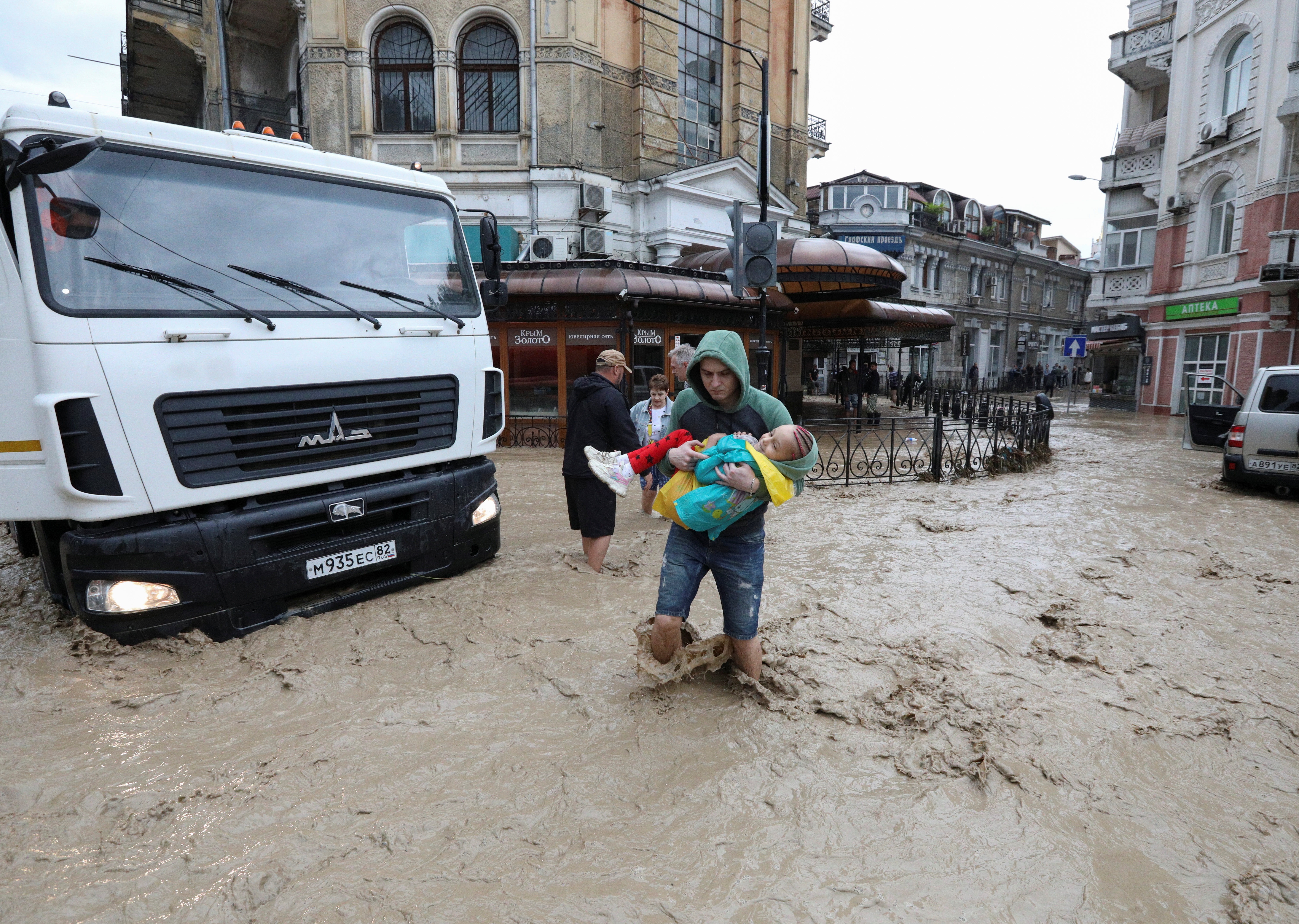 People cross a flooded street following heavy rainfall in Yalta, Crimea June 18, 2021. REUTERS/Alexey Pavlishak