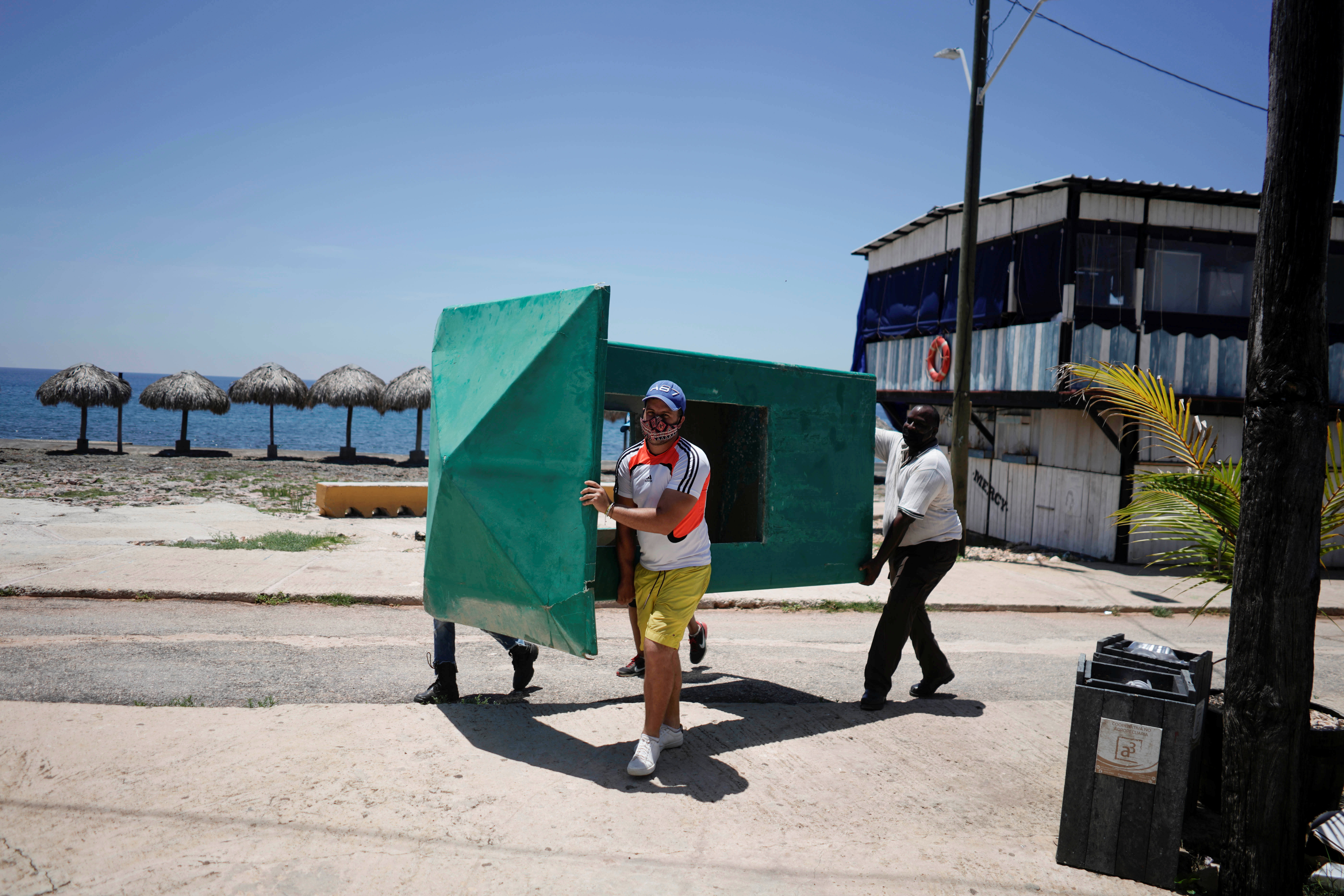 Workers carry a sentry box as Hurricane Elsa approaches the island, Havana, Cuba, July 2, 2021. REUTERS/Alexandre Meneghini