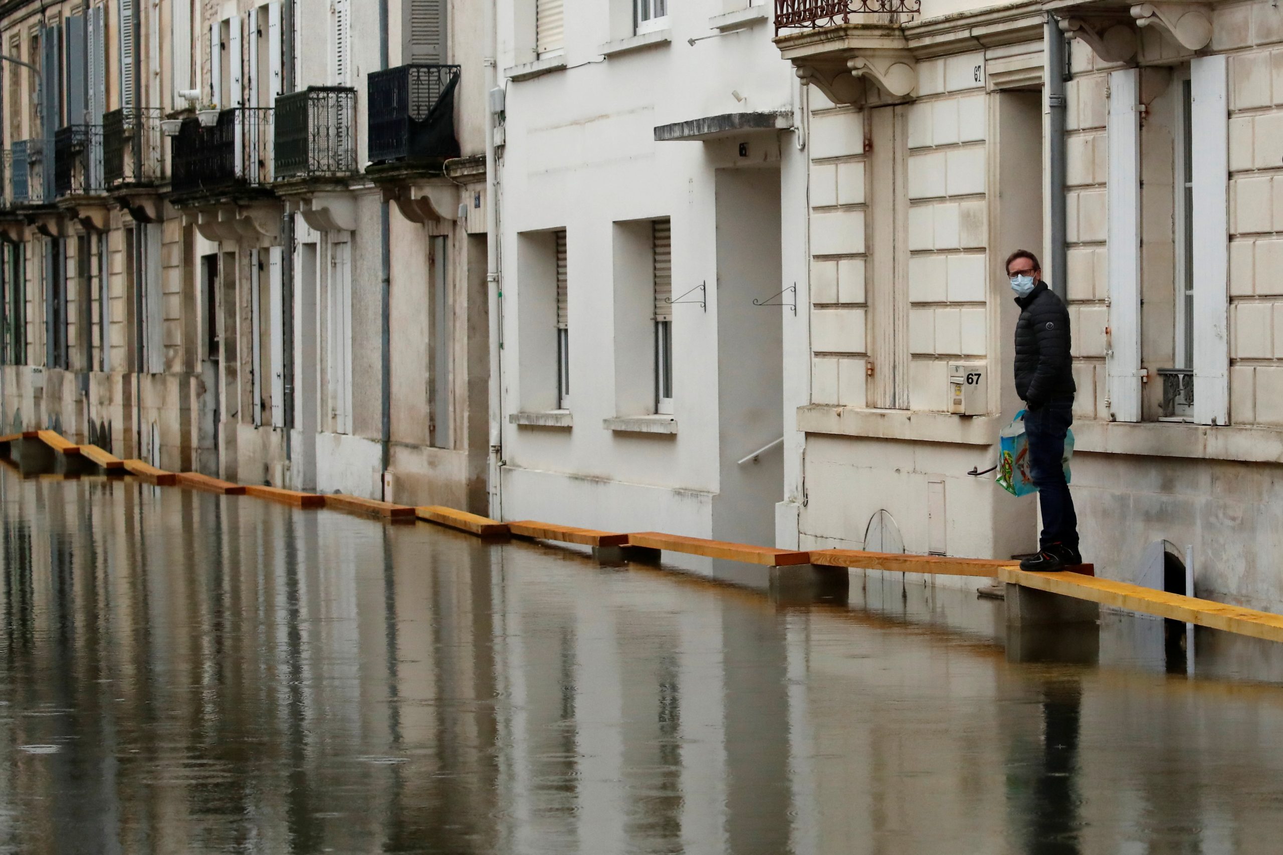 A resident walks on a makeshift walkway in a flooded area as the Charente River overflows in Saintes after days of rainy weather causing flooding in western France, France, February 8, 2021. REUTERS/Stephane Mahe