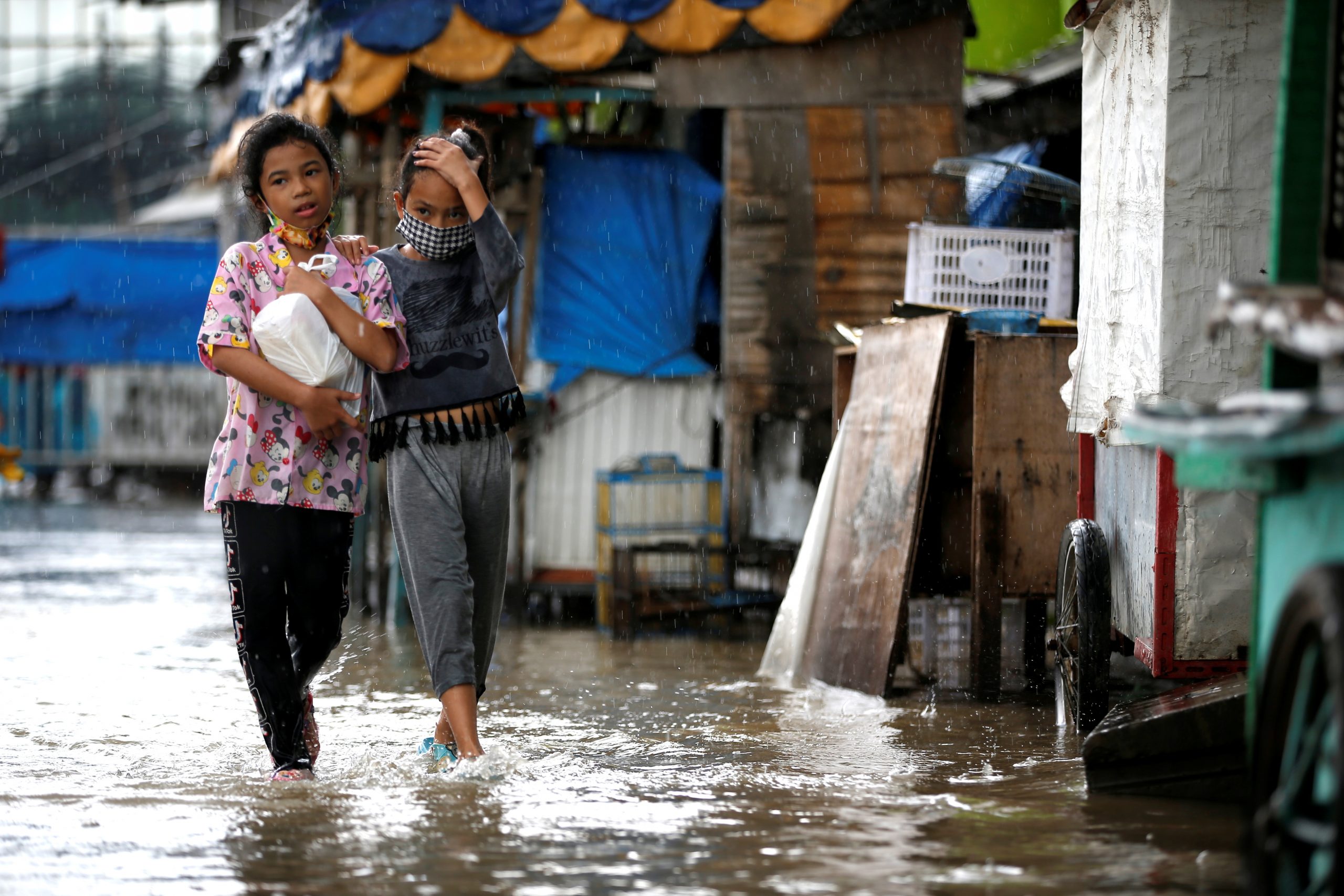 Girls walk along a street affected by floods in  Jakarta, Indonesia, February 8, 2021. REUTERS/Willy Kurniawan