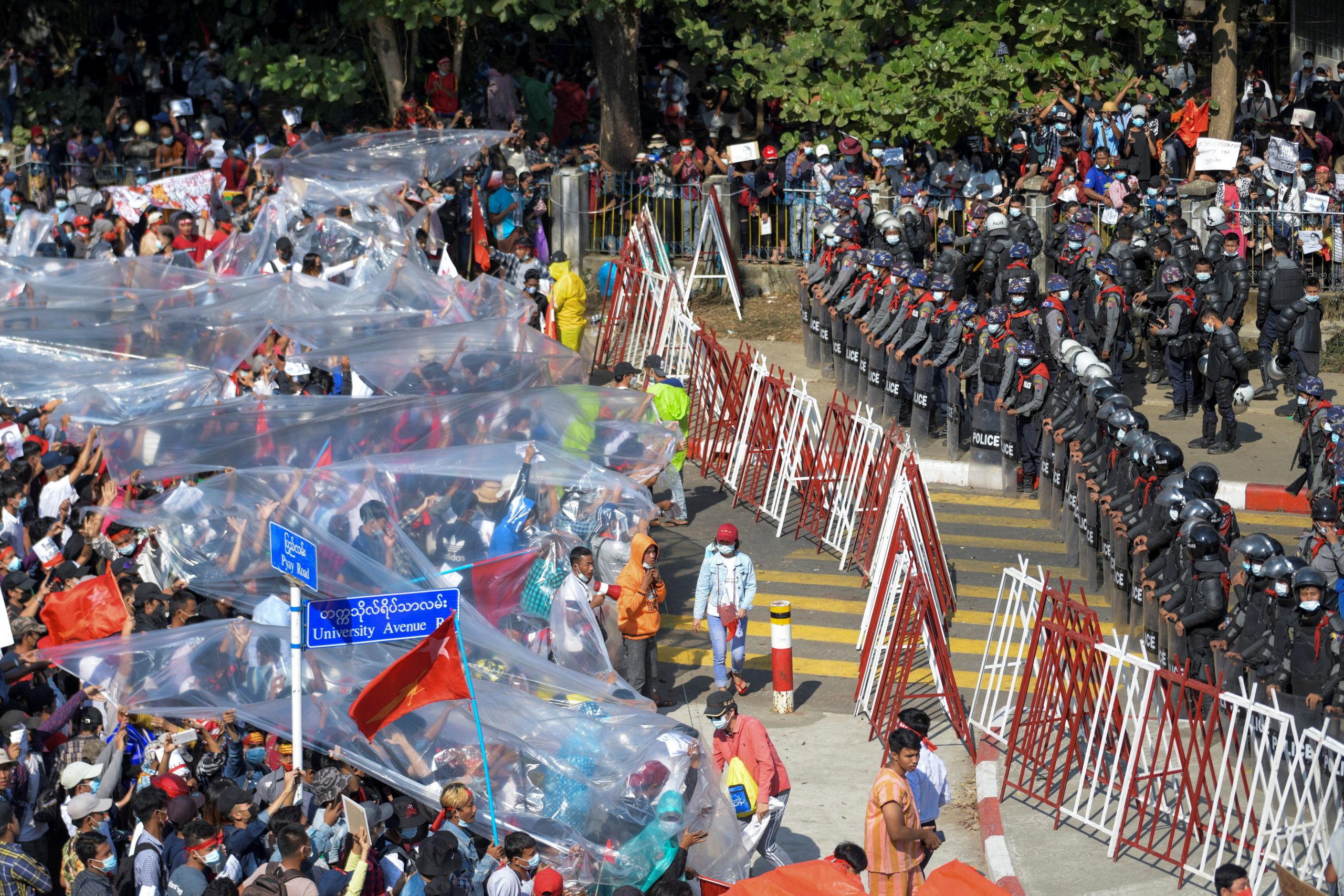 People cover with plastic in case of a water canon use during a rally against the military coup and to demand the release of elected leader Aung San Suu Kyi, in Yangon, Myanmar, February 9, 2021. REUTERS/Stringer