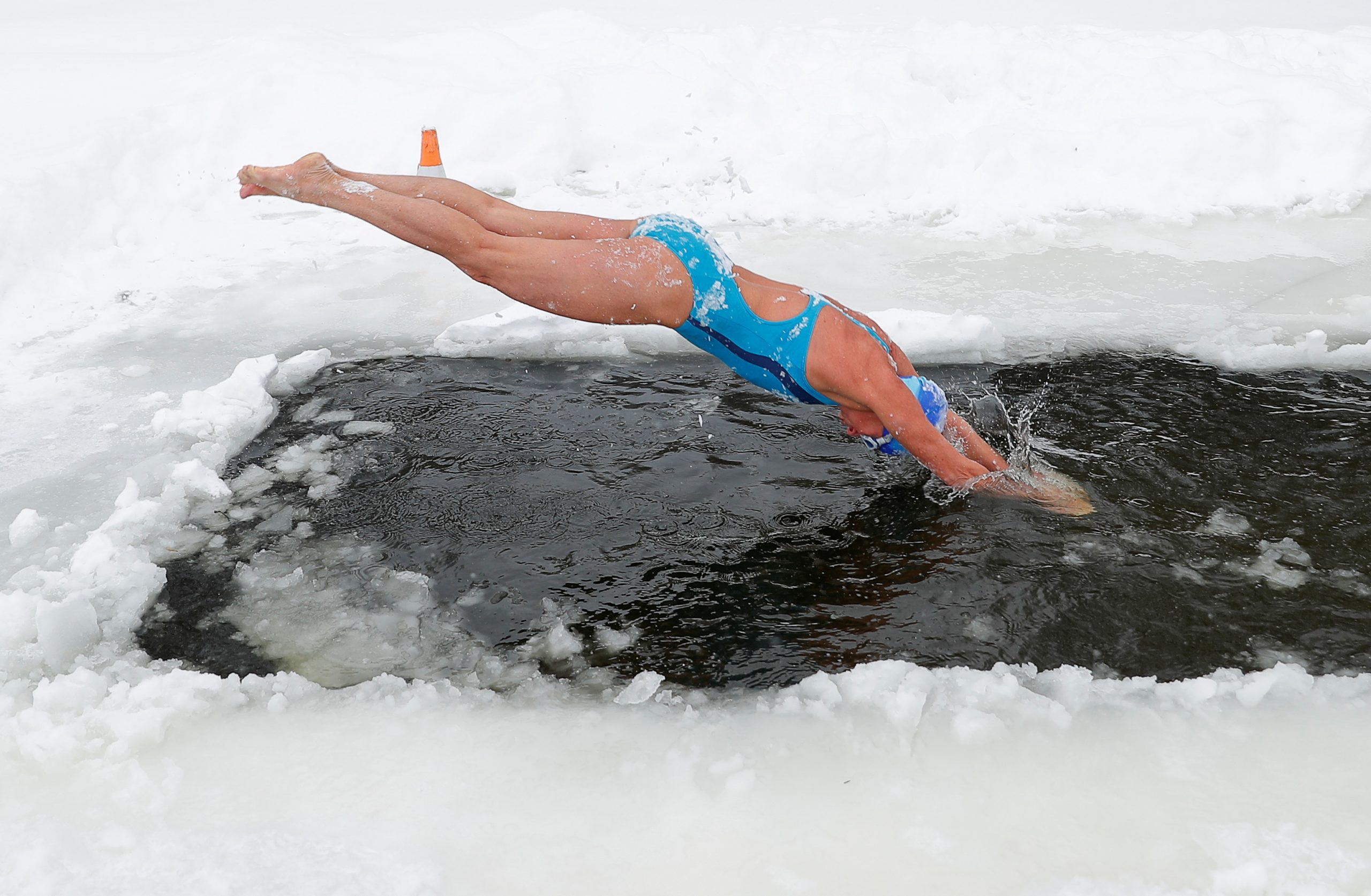 Natalya Seraya, chairwoman of "Walruses of the Capital" winter swimming club, dives into the icy waters of the Moskva River on a frosty day in Moscow, Russia February 13, 2021. REUTERS/Evgenia Novozhenina