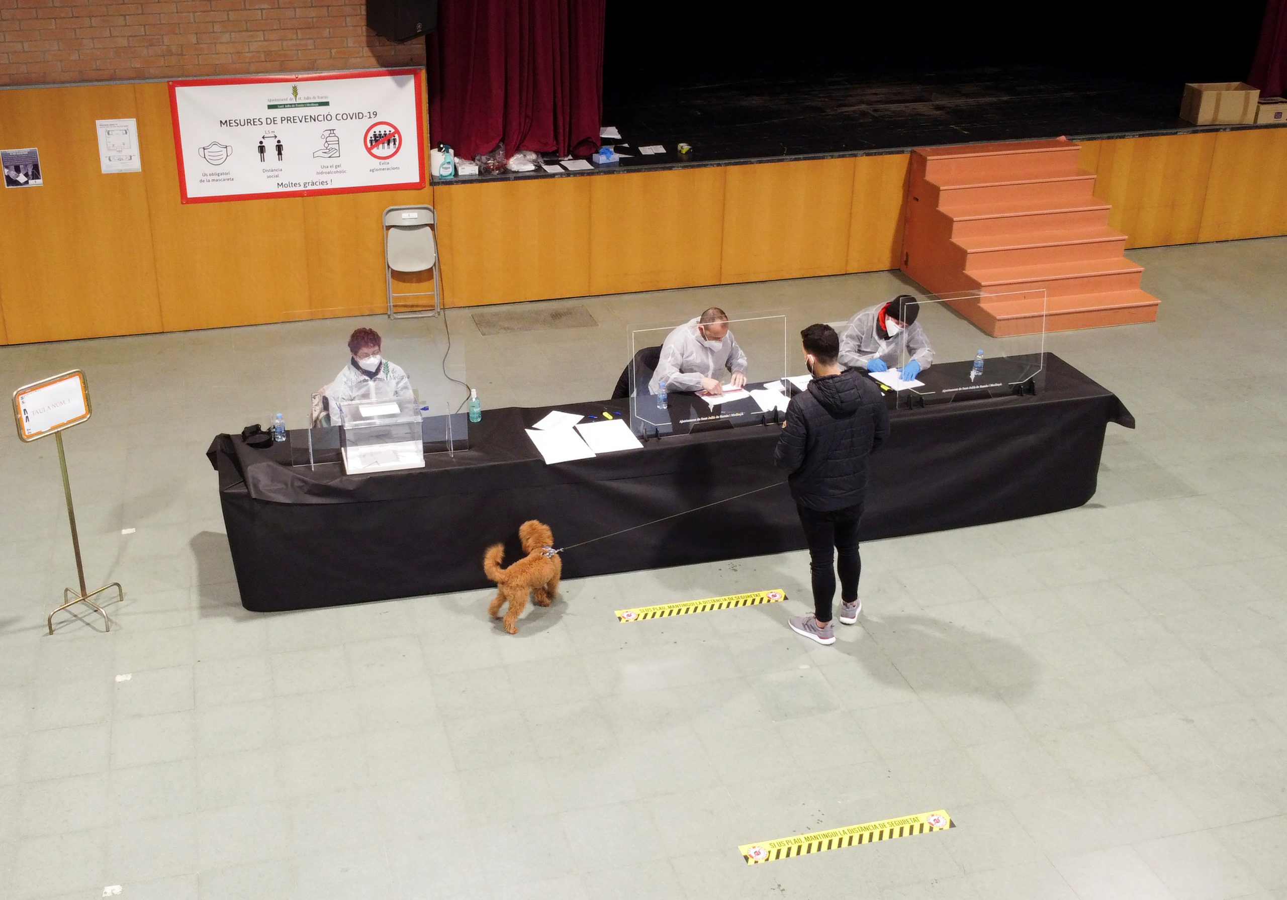 A man with his dog queues to cast his vote at a polling station during regional elections in Catalonia, amid the outbreak of the coronavirus disease (COVID-19), in Sant Julia de Ramis, near Girona, Spain, February 14, 2021. REUTERS/Nacho Doce