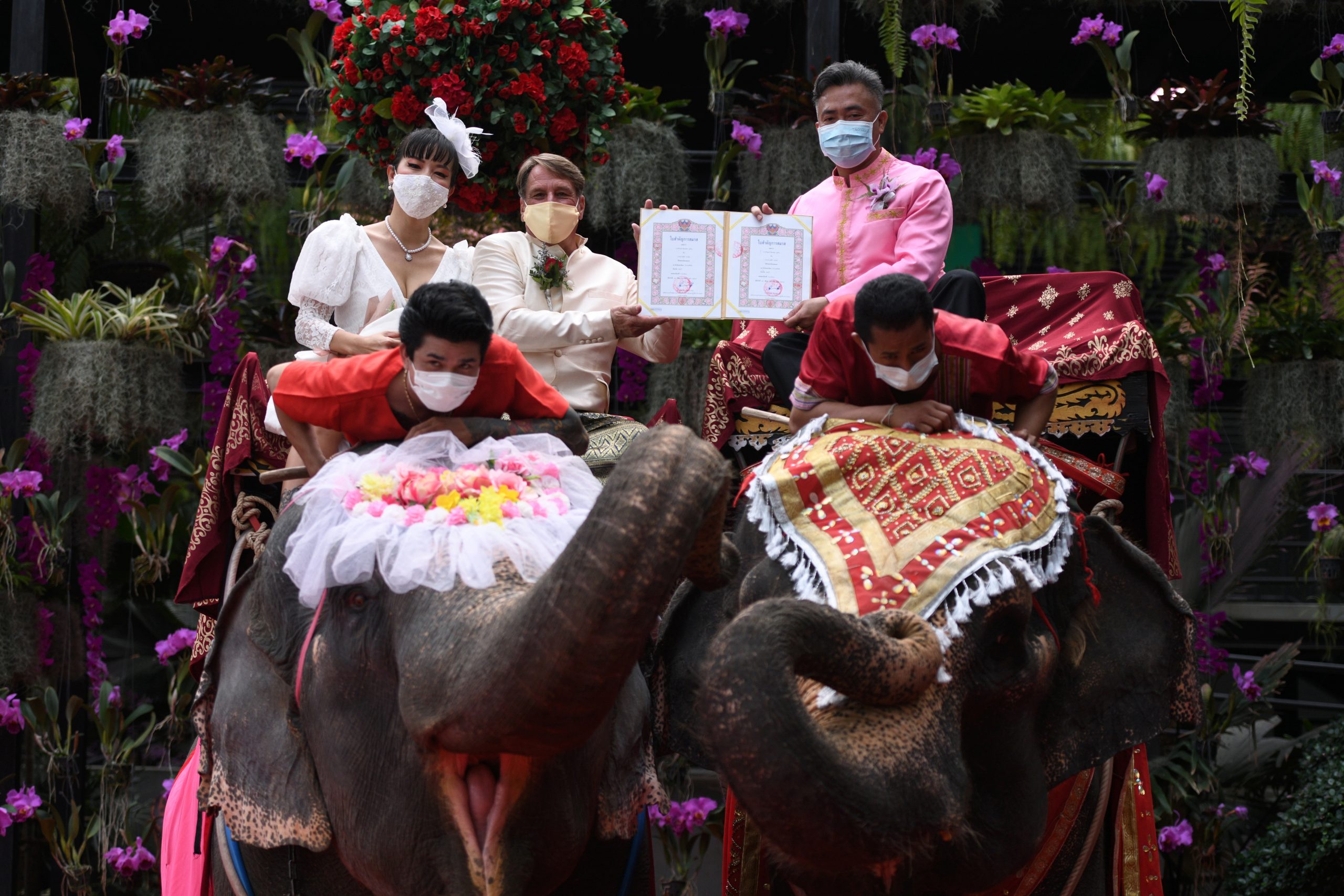A couple receives marriage certificates from a provincial officer as they ride elephants during a Valentine's Day celebration at the Nong Nooch Tropical Garden in Chonburi province, Thailand, February 14, 2021. REUTERS/Chalinee Thirasupa