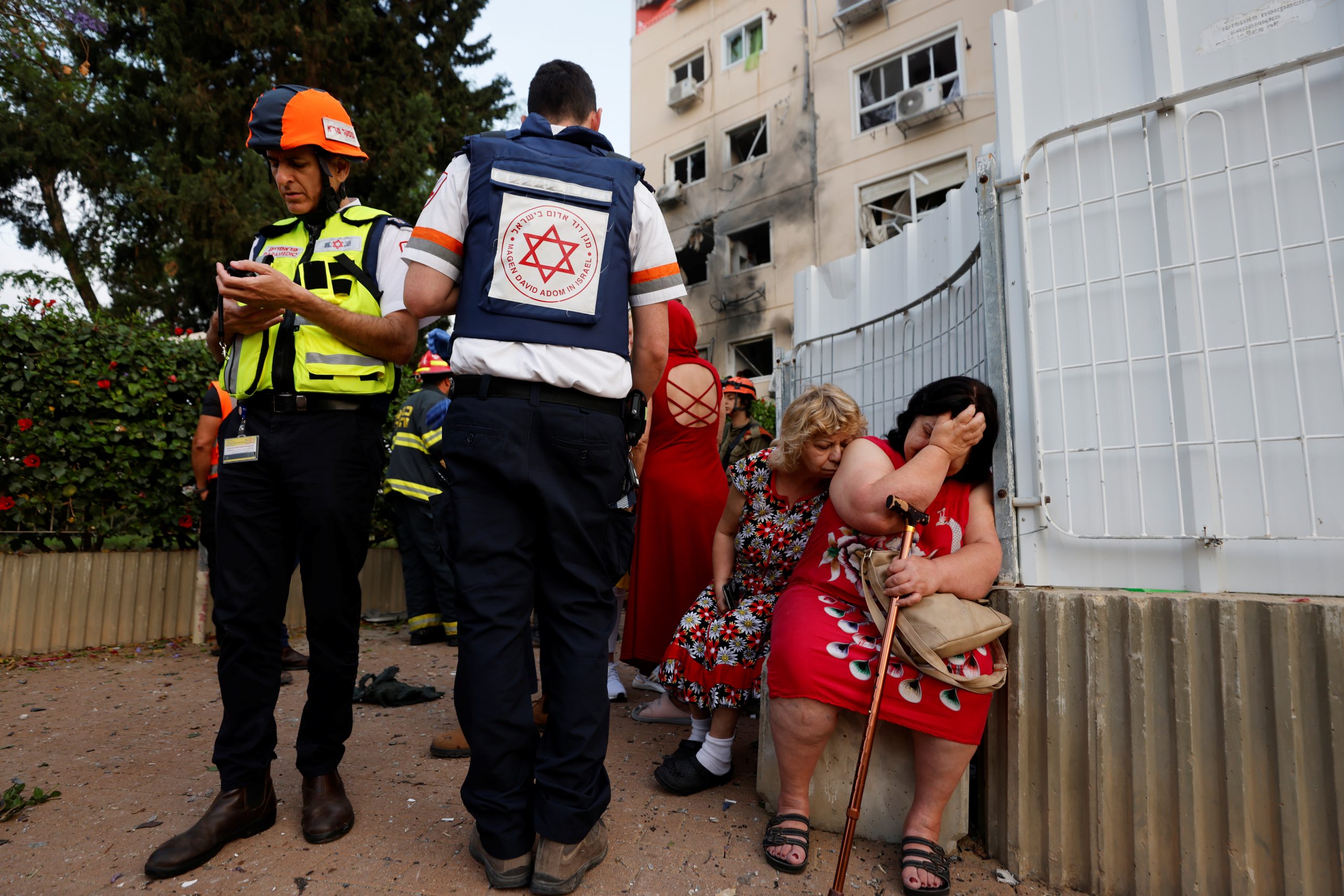 Israeli medics stand near women as they react after a residential building was damaged by a rocket launched from the Gaza Strip, in Ashkelon, southern Israel May 11, 2021. REUTERS/Amir Cohen