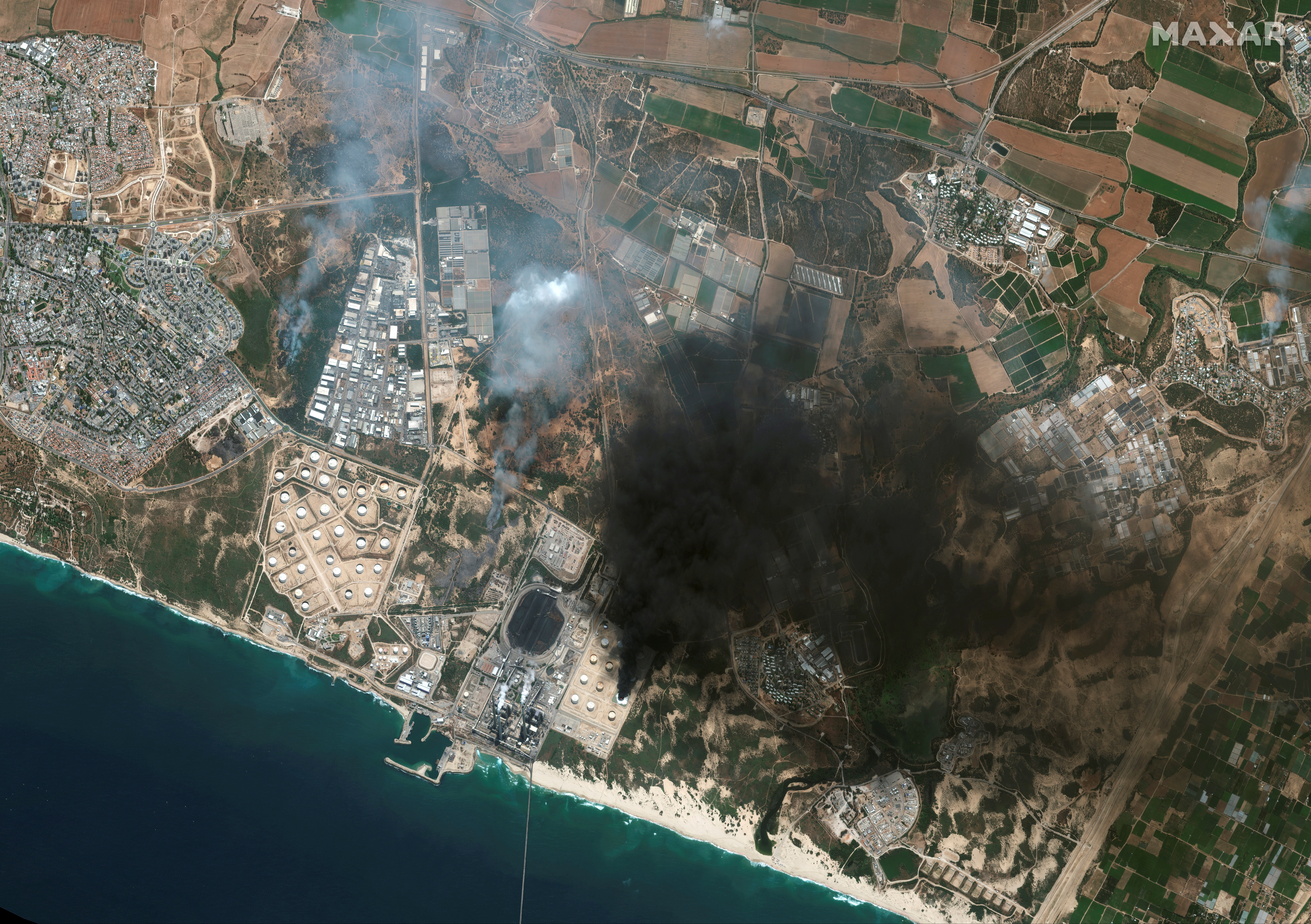 A satellite view shows an overview of Ashkelon and burning storage tanks in southern Israel