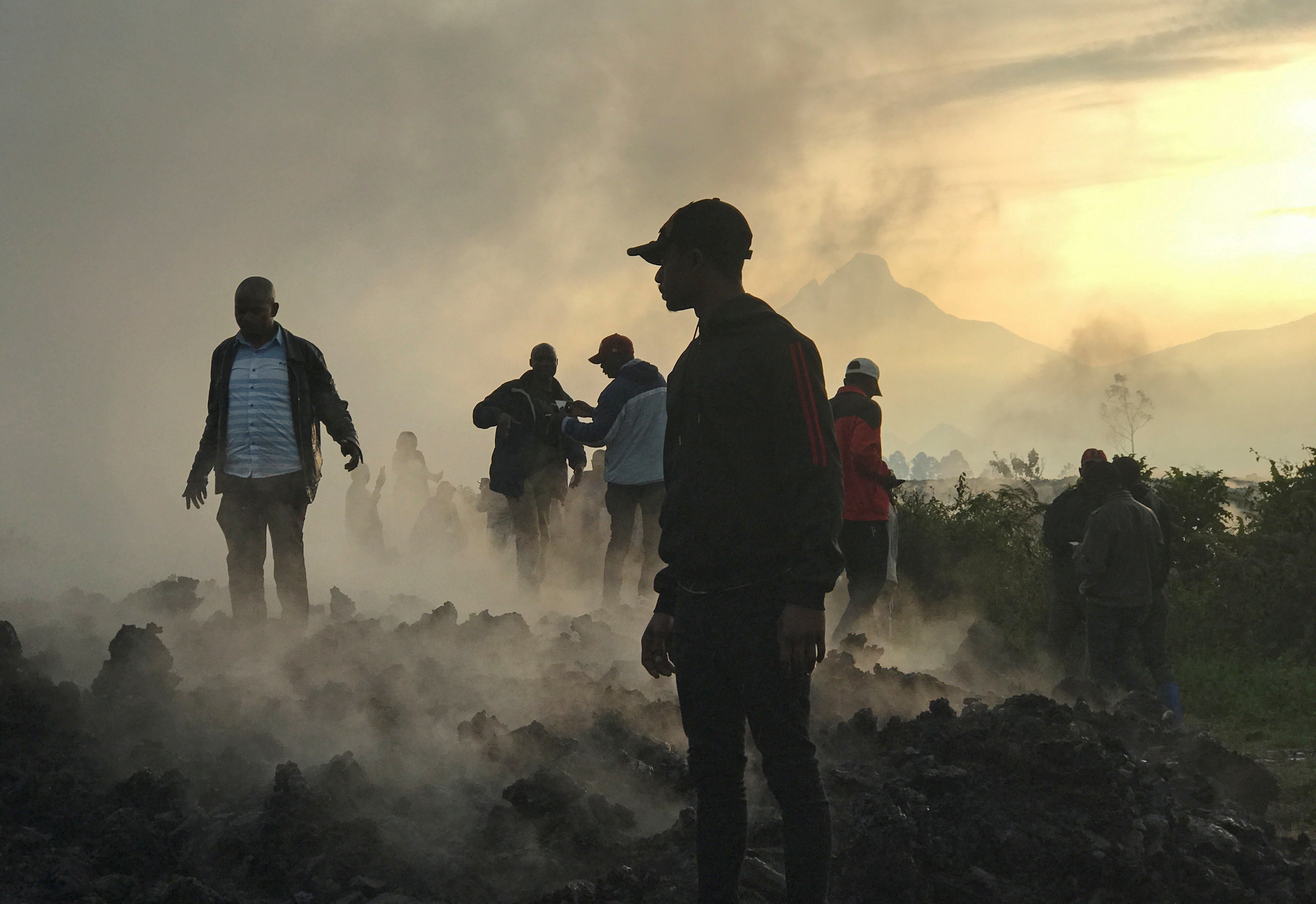Residents walk near destroyed homes with the smouldering lava deposited by the eruption of Mount Nyiragongo volcano near Goma, in the Democratic Republic of Congo May 23, 2021. REUTERS/Djaffar Al Katanty       NO RESALES. NO ARCHIVES.