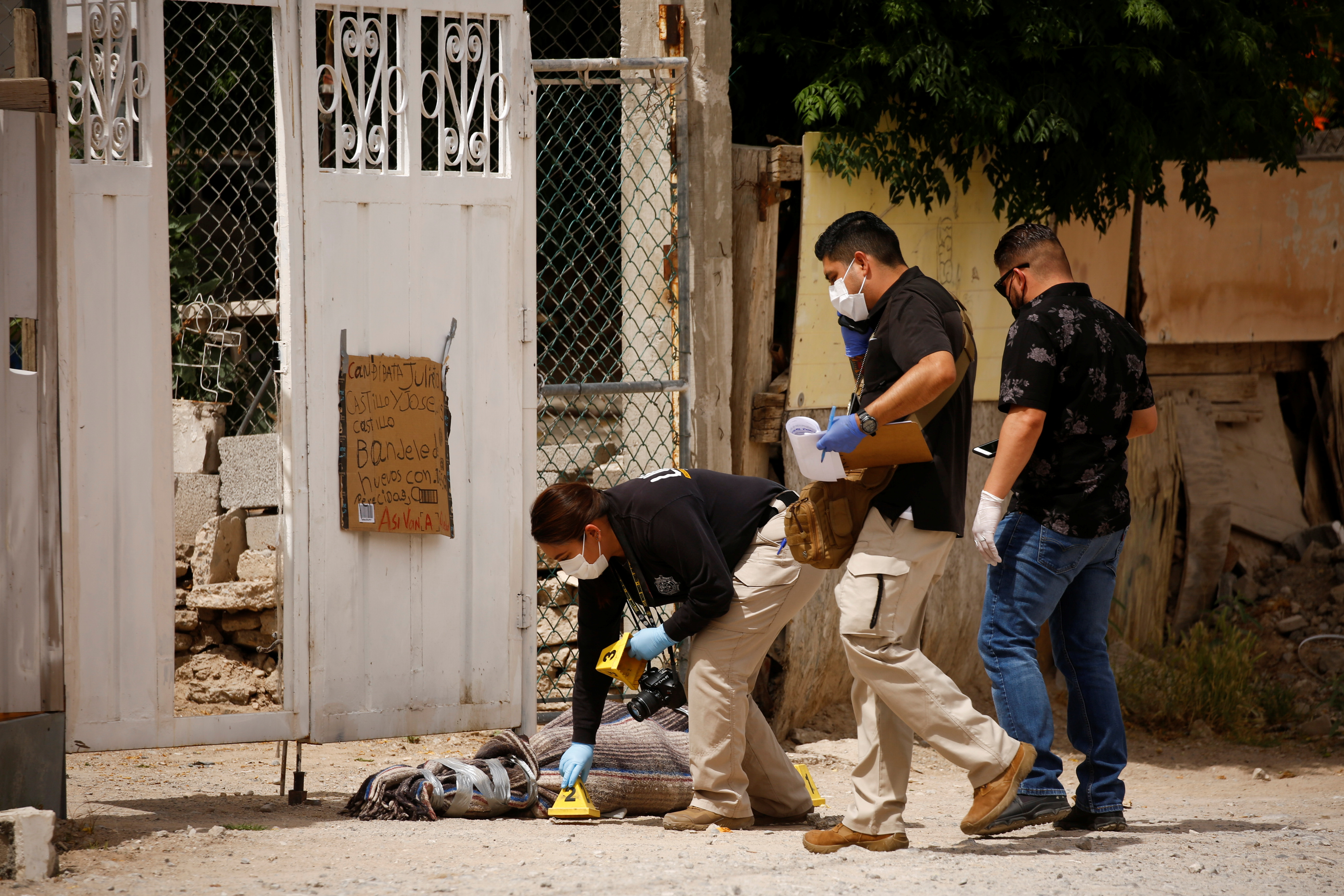 Meksiko, narko mafija, Forensic investigators work at a scene where assailants left a package and a threat message taped to the gate of the house of Leticia Castillo, in Ciudad Juarez