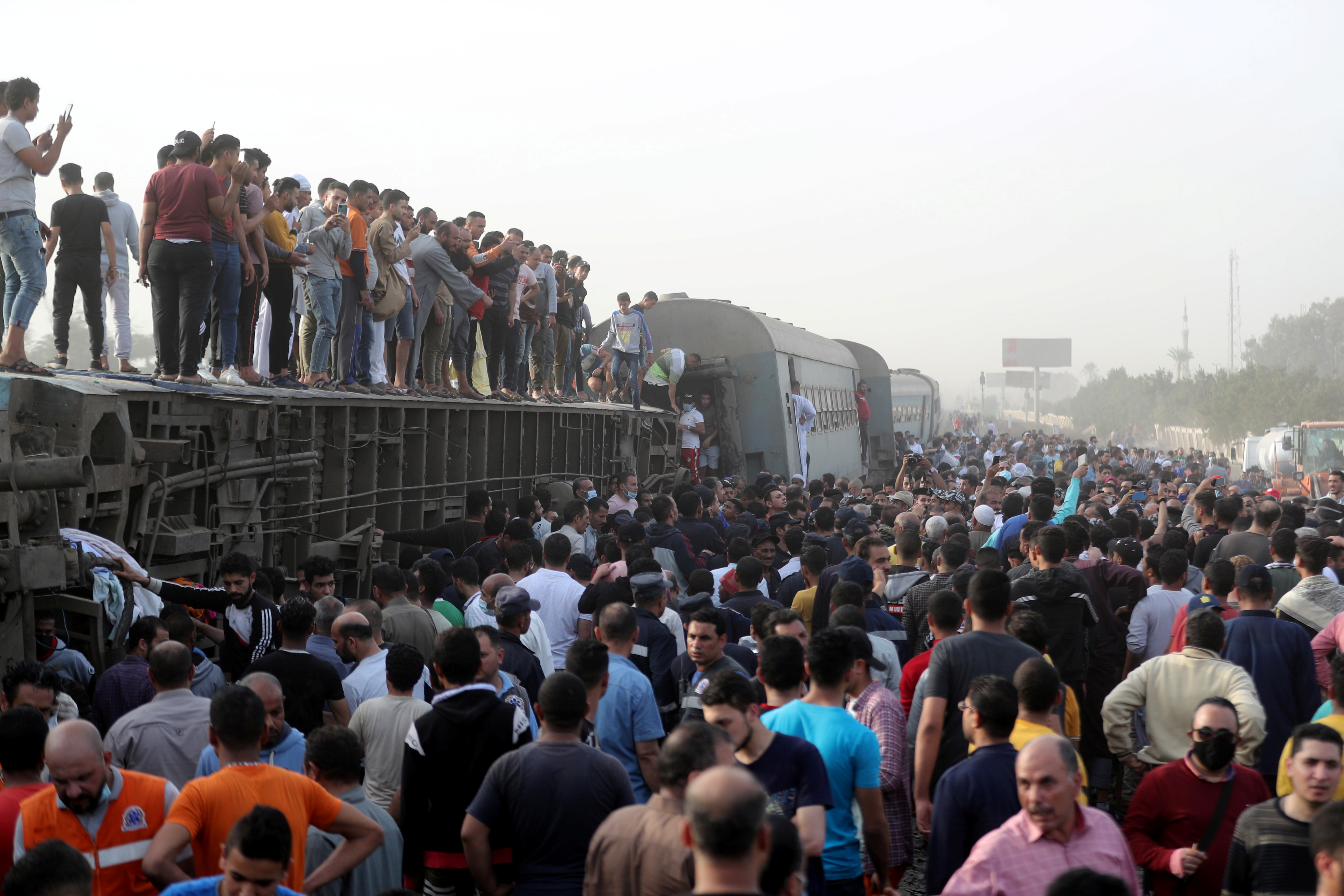 People gather at the site where train carriages derailed in Qalioubia province, north of Cairo, Egypt April 18, 2021. REUTERS/Mohamed Abd El Ghany
