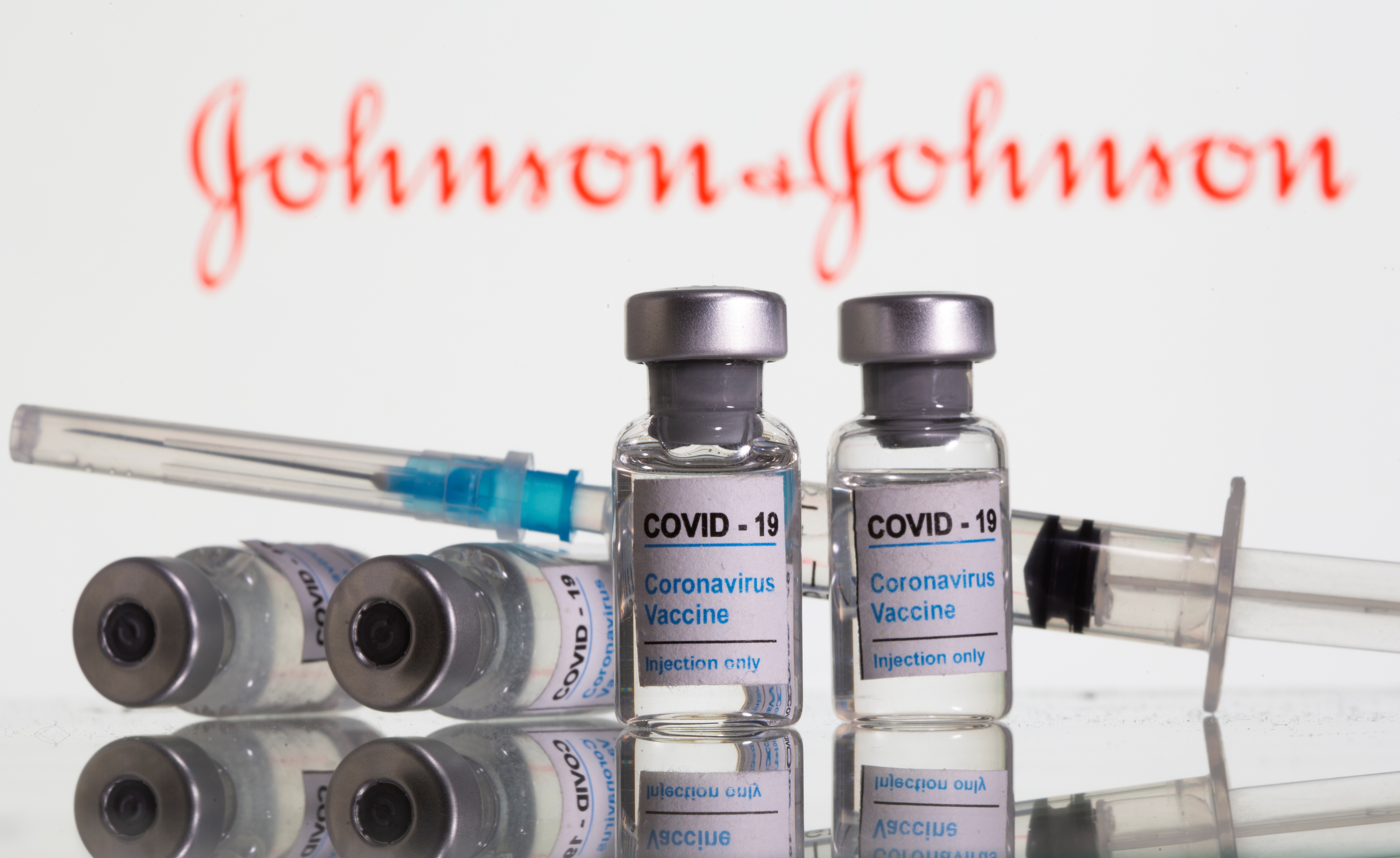 Vials labelled "COVID-19 Coronavirus Vaccine" and sryinge are seen in front of displayed J&amp;J logo in this illustration