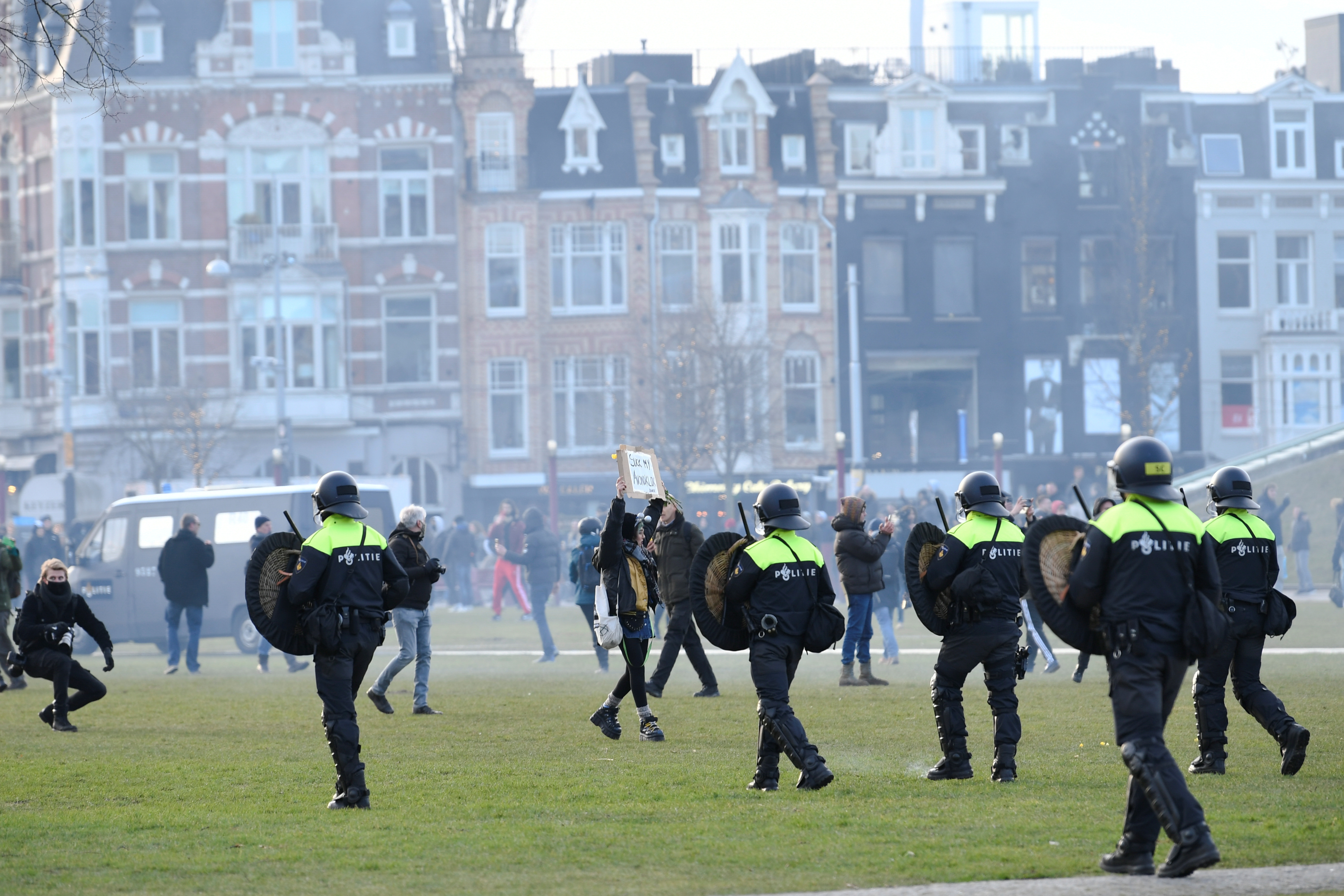 A demonstrator holds a banner as riot police officers make them leave from a protest against restrictions put in place to curb the spread of the coronavirus disease (COVID-19), in Amsterdam, Netherlands, January 31, 2021. REUTERS/Stringer
