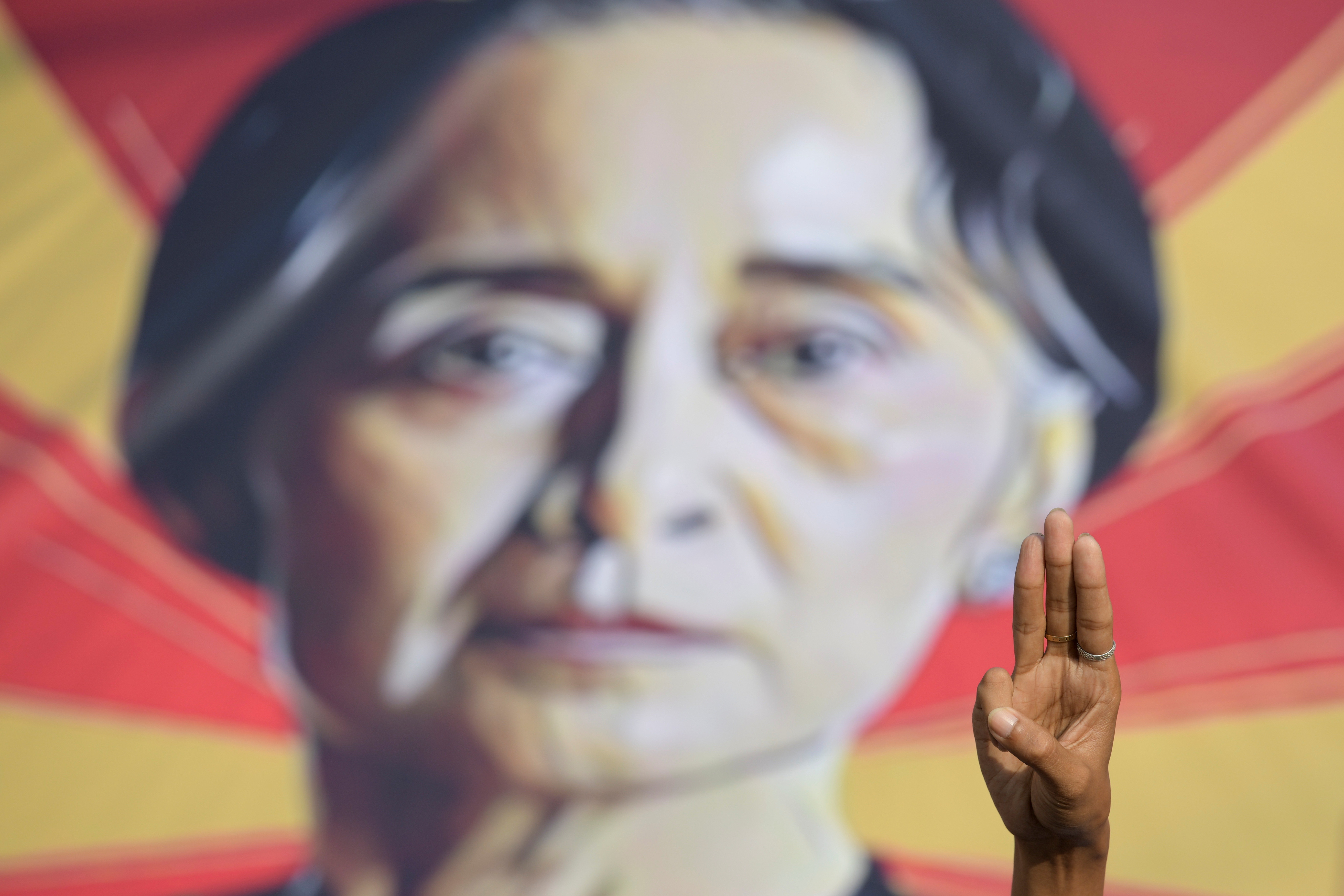 A person shows the three-fingers salute in front of a placard with the image of Aung San Suu Kyi during a protest against the military coup in Yangon, Myanmar, February 15, 2021. REUTERS/Stringer