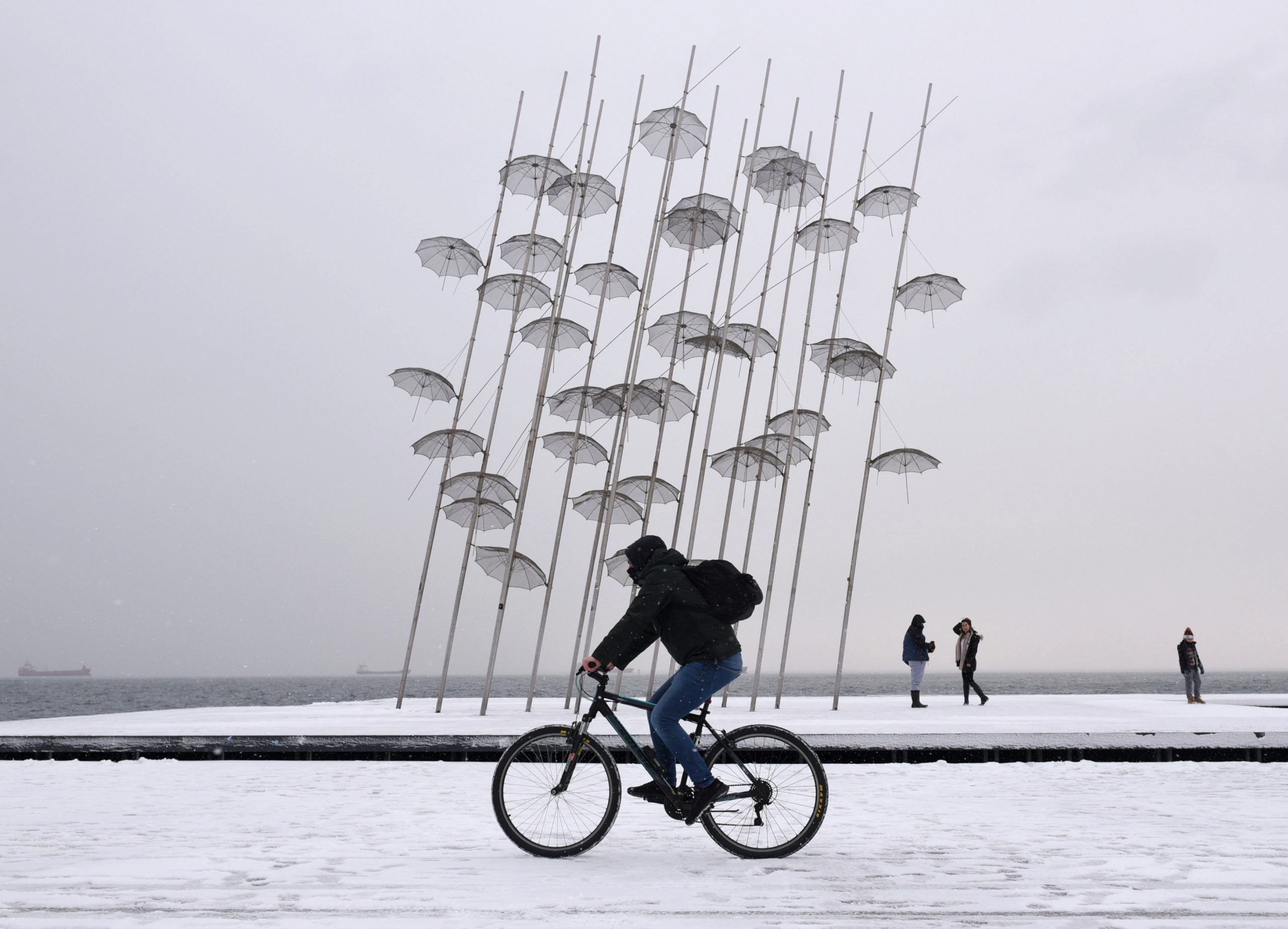 A man rides his bike during heavy snowfall, on the  promenade of Thessaloniki, Greece February 14, 2021. REUTERS/Alexandros Avramidis