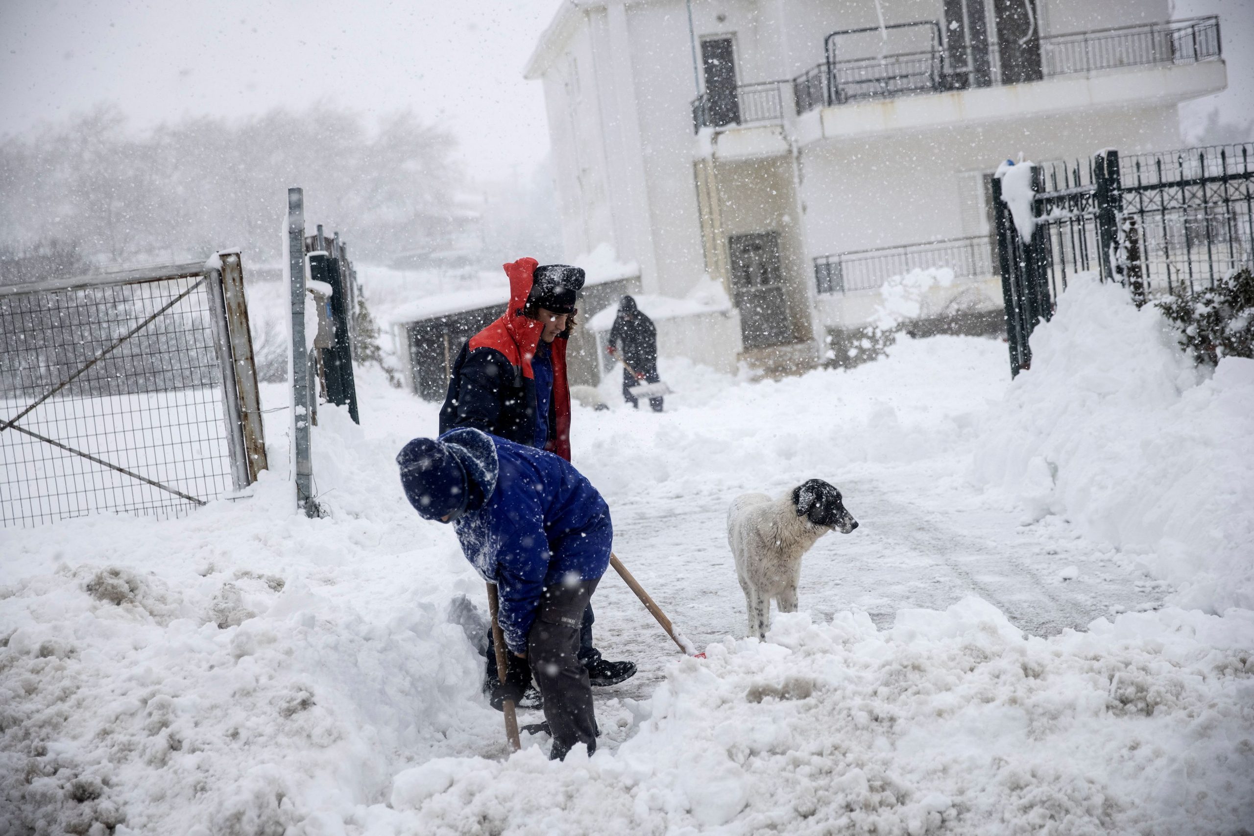 Men shovel snow from the entrance of their property during heavy snowfall, in the village of Kapandriti, Greece, February 15, 2021. REUTERS/Alkis Konstantinidis