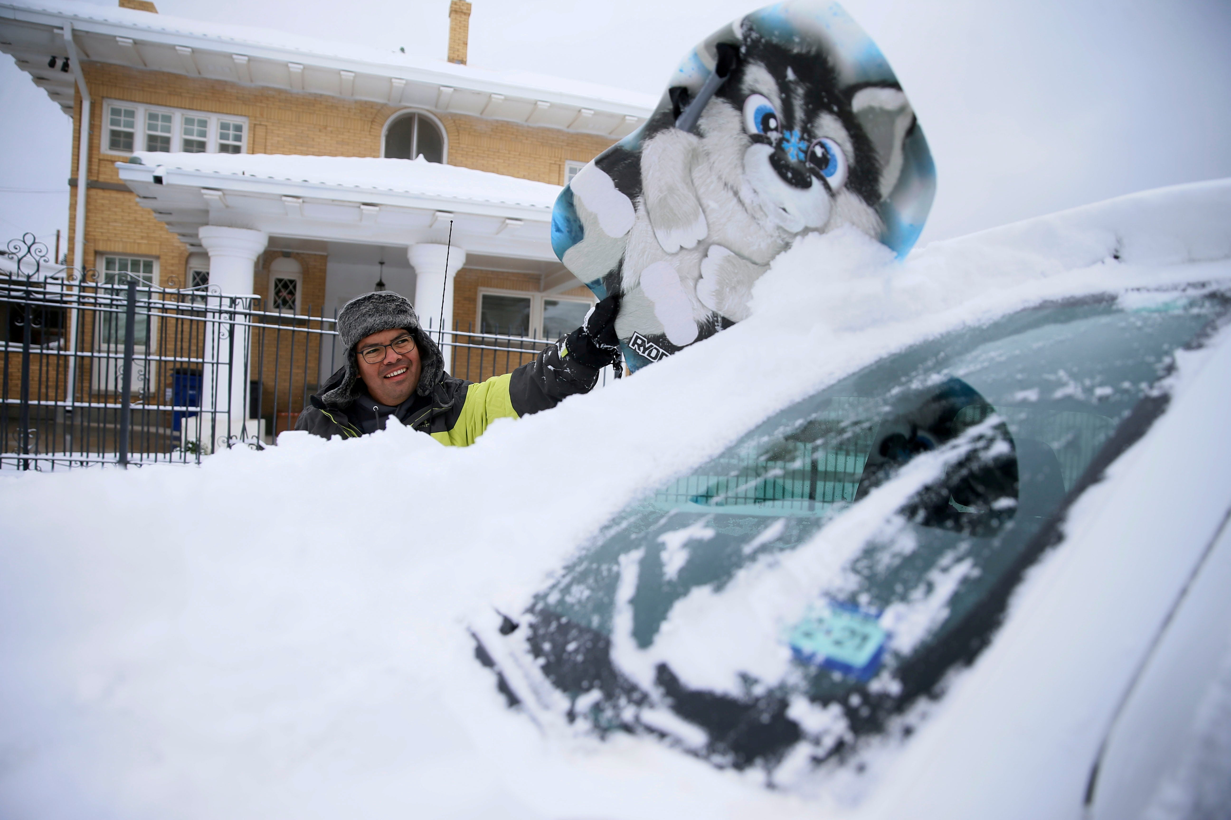 FILE PHOTO: Francisco Sanchez wipes snow off his car with a boogie board before going out sledding with his kids in El Paso