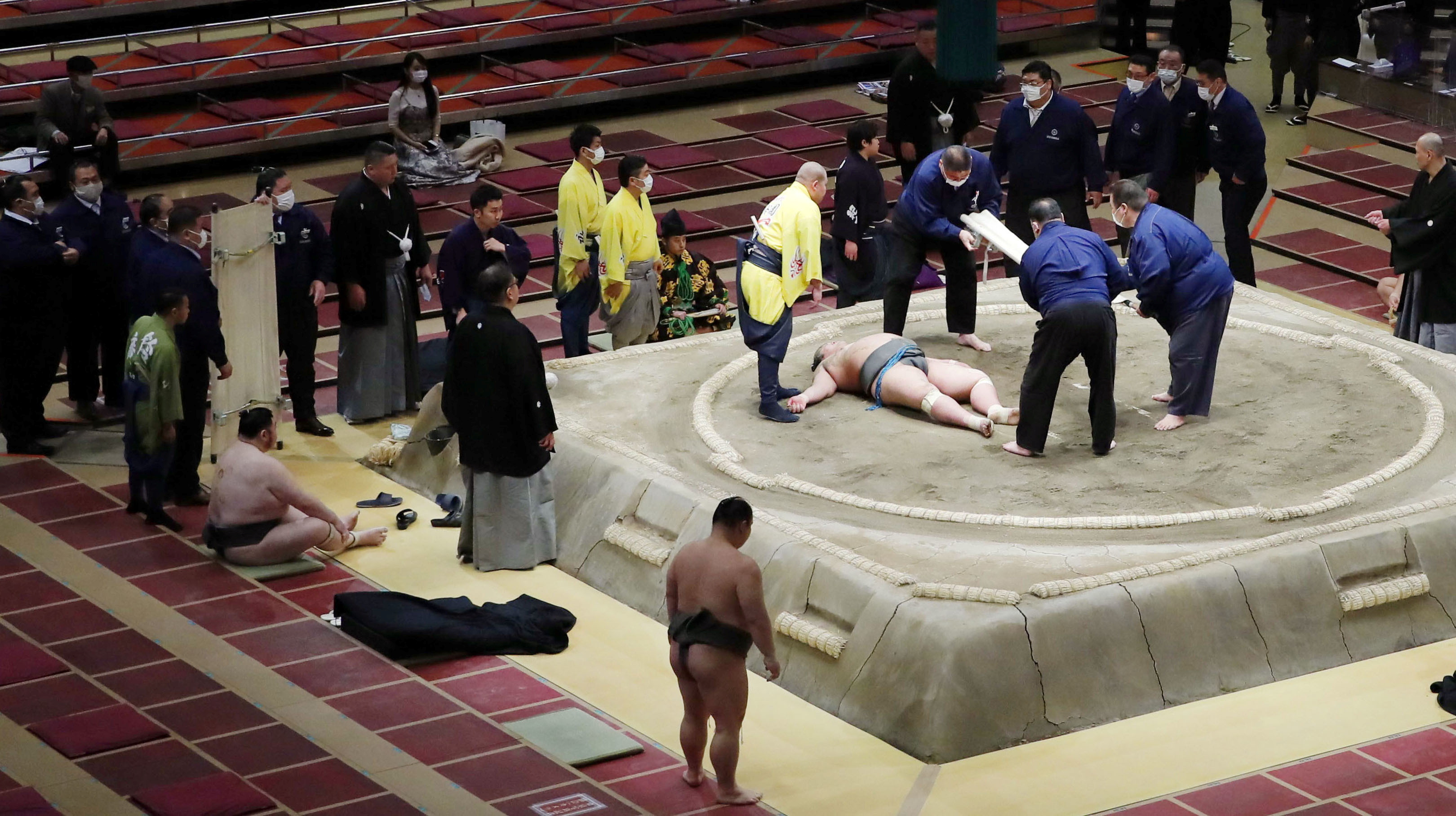 Officials gather around 28-year-old sumo wrestler Hibikiryu after he collapsed in the ring during the sumo grand tournament in Tokyo