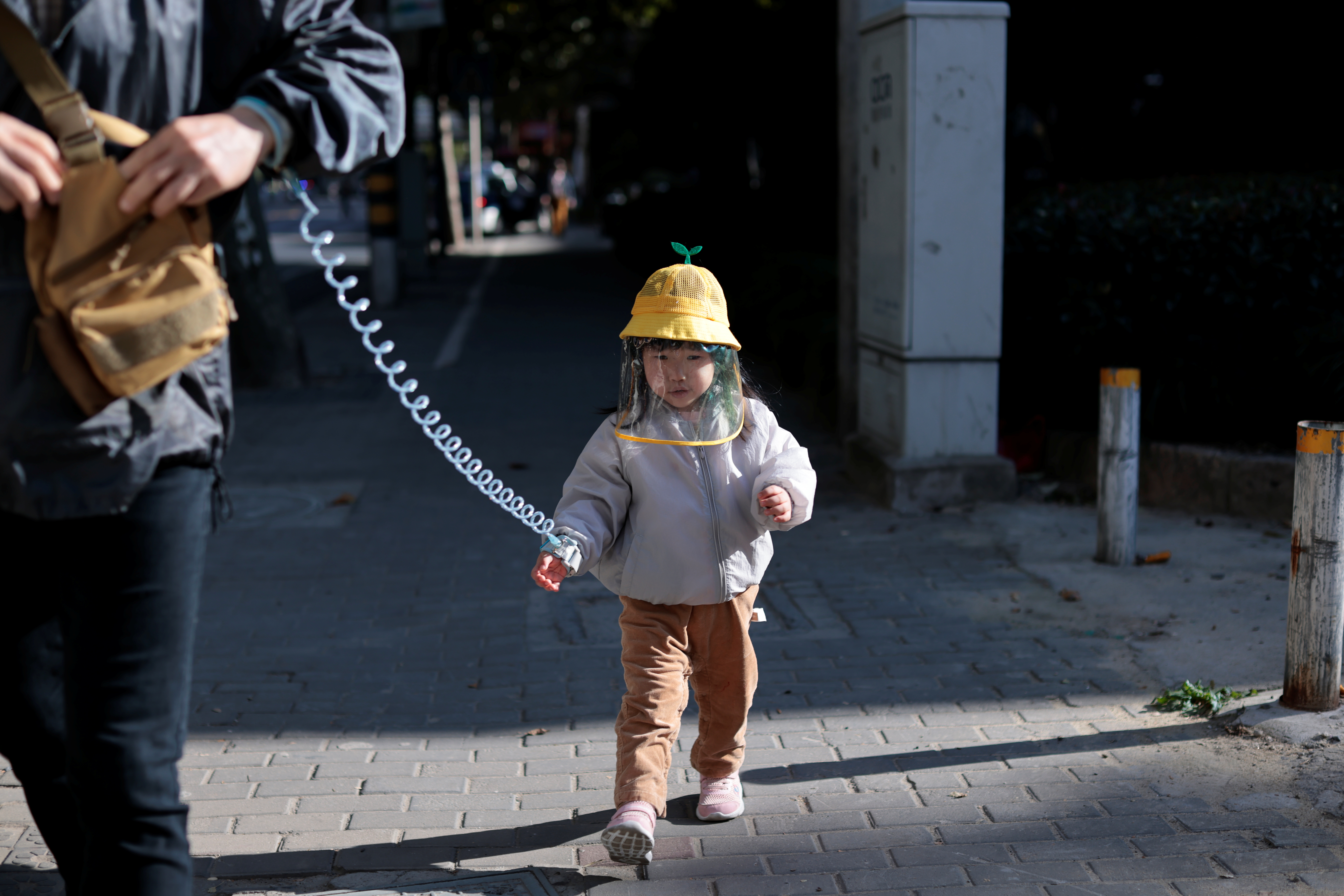 A little girl wearing a protective face covering walks with her father on a street, following the coronavirus disease (COVID-19) outbreak in Shanghai, China October 25, 2020. REUTERS/Aly Song