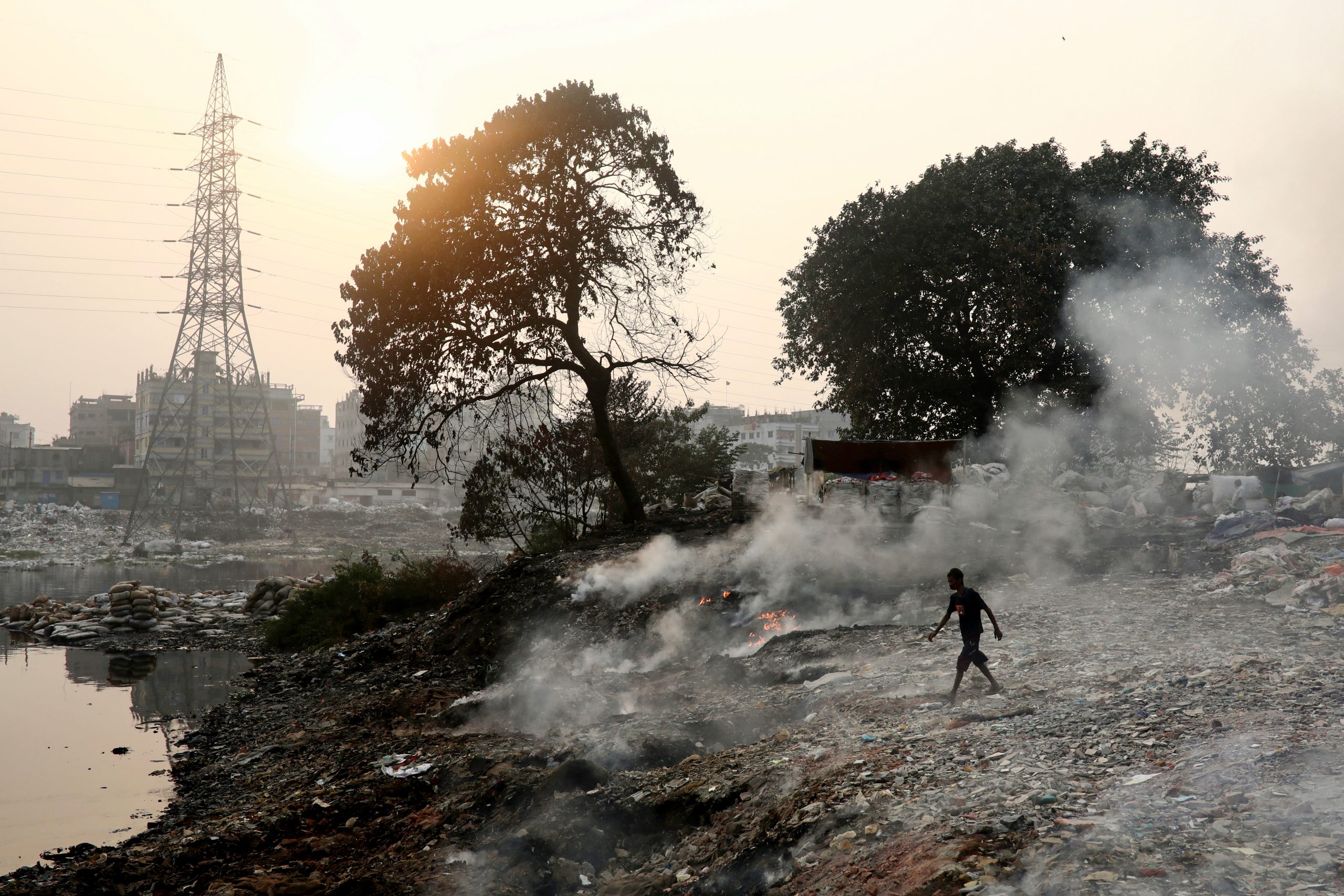 A man walks through the smoke that raises from burning wastes in Dhaka, Bangladesh, December 22, 2020. REUTERS/Mohammad Ponir Hossain