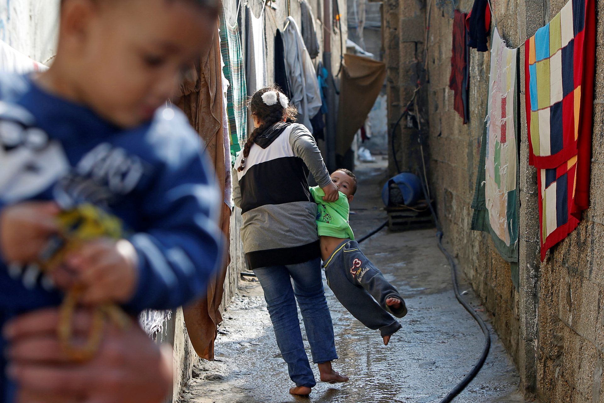 A Palestinian girl carries a boy outside her family's home at Beach refugee camp in Gaza City November 8, 2020. REUTERS/Mohammed Salem